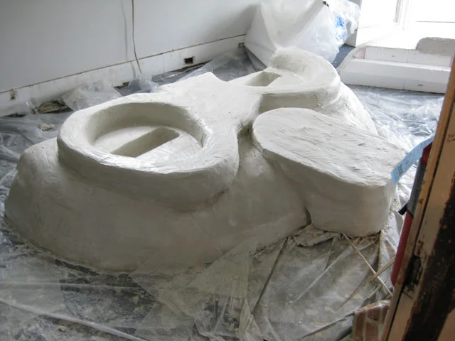  The shape was carved out of block of foam held together by countless dowel rods. The final shape was then coated in layers of cement and mesh.&nbsp; 