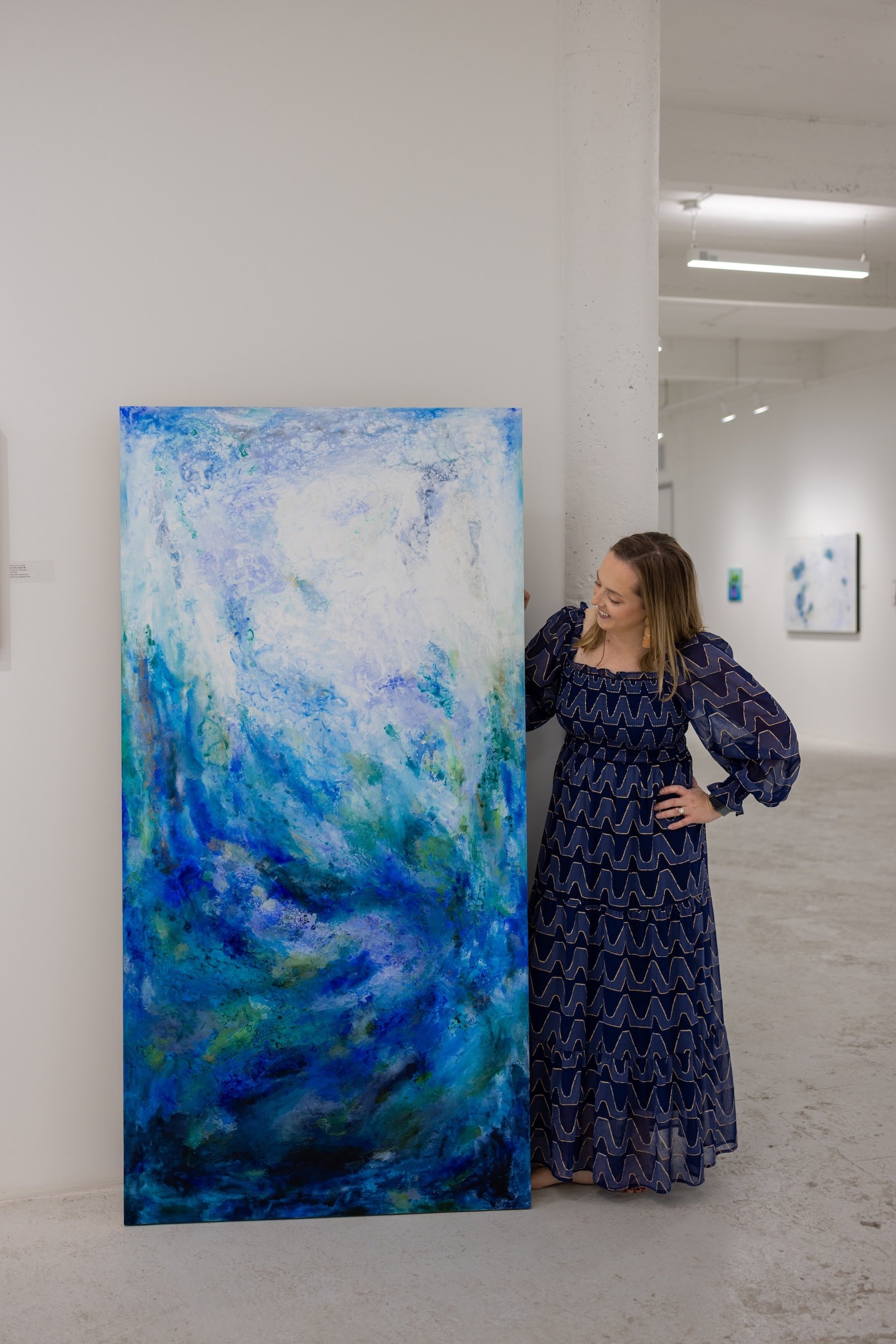 Artist Allyson Caire pictured with an oversized statement abstract painting at Winter Street Studios in Sawyer Yards. 