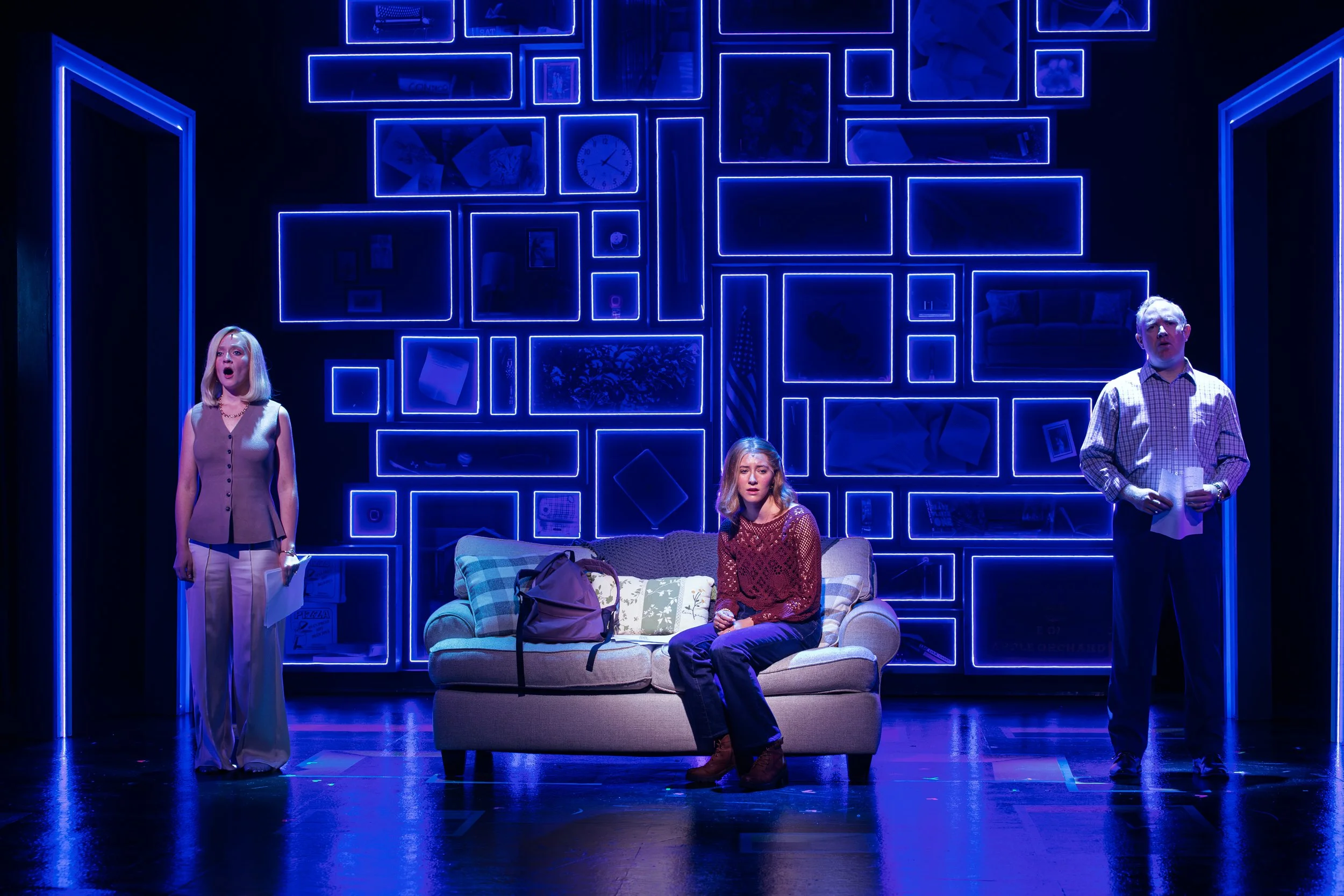 Three women and one man perform on a stage with a blue neon light wall behind them. Maggie Bera playing Cynthia Murphy in Dear Evan Hansen at the Engeman Theater.