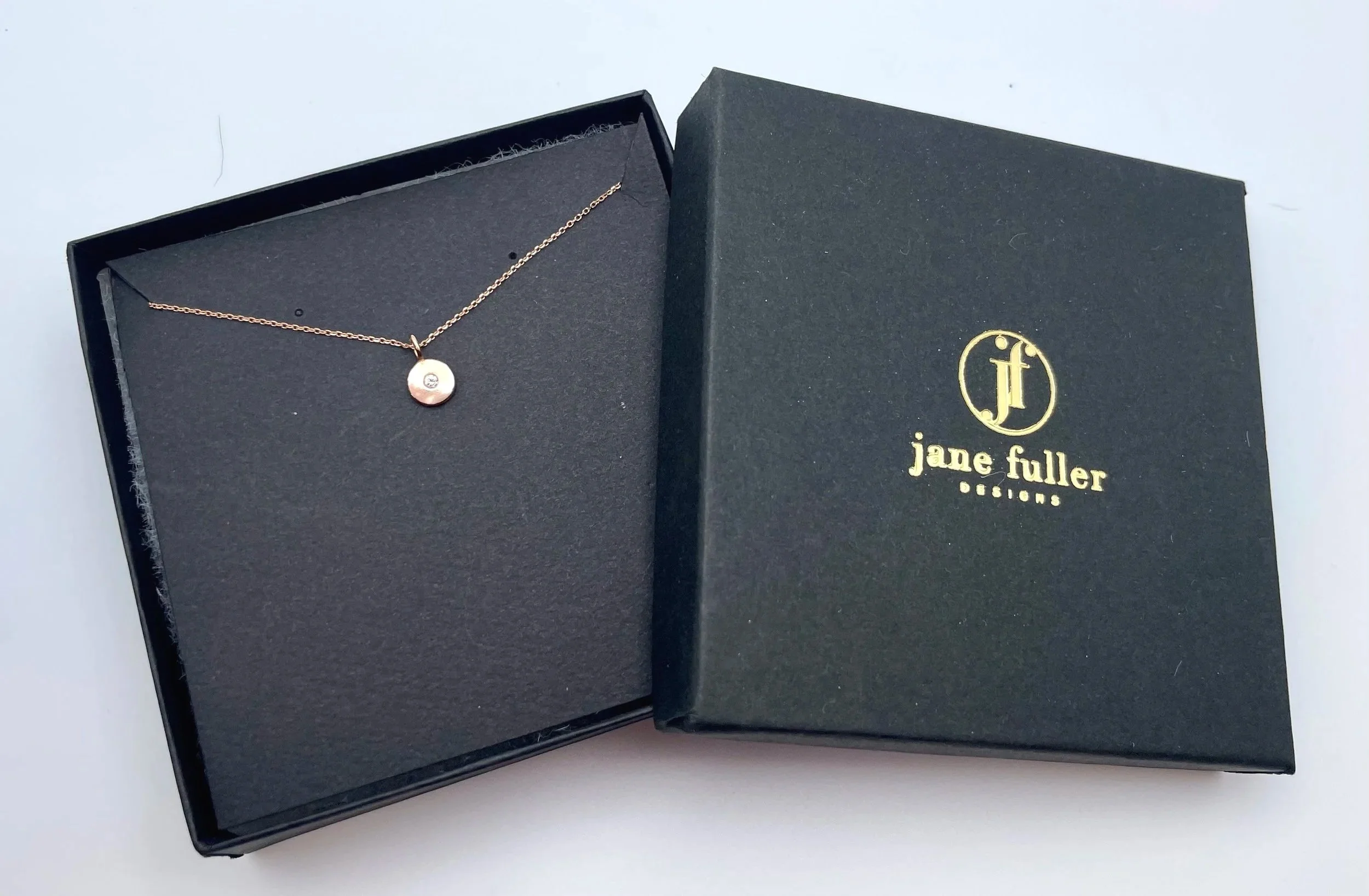 14k rose gold disc necklace with tiny diamond shown in Jane Fuller Designs gift box