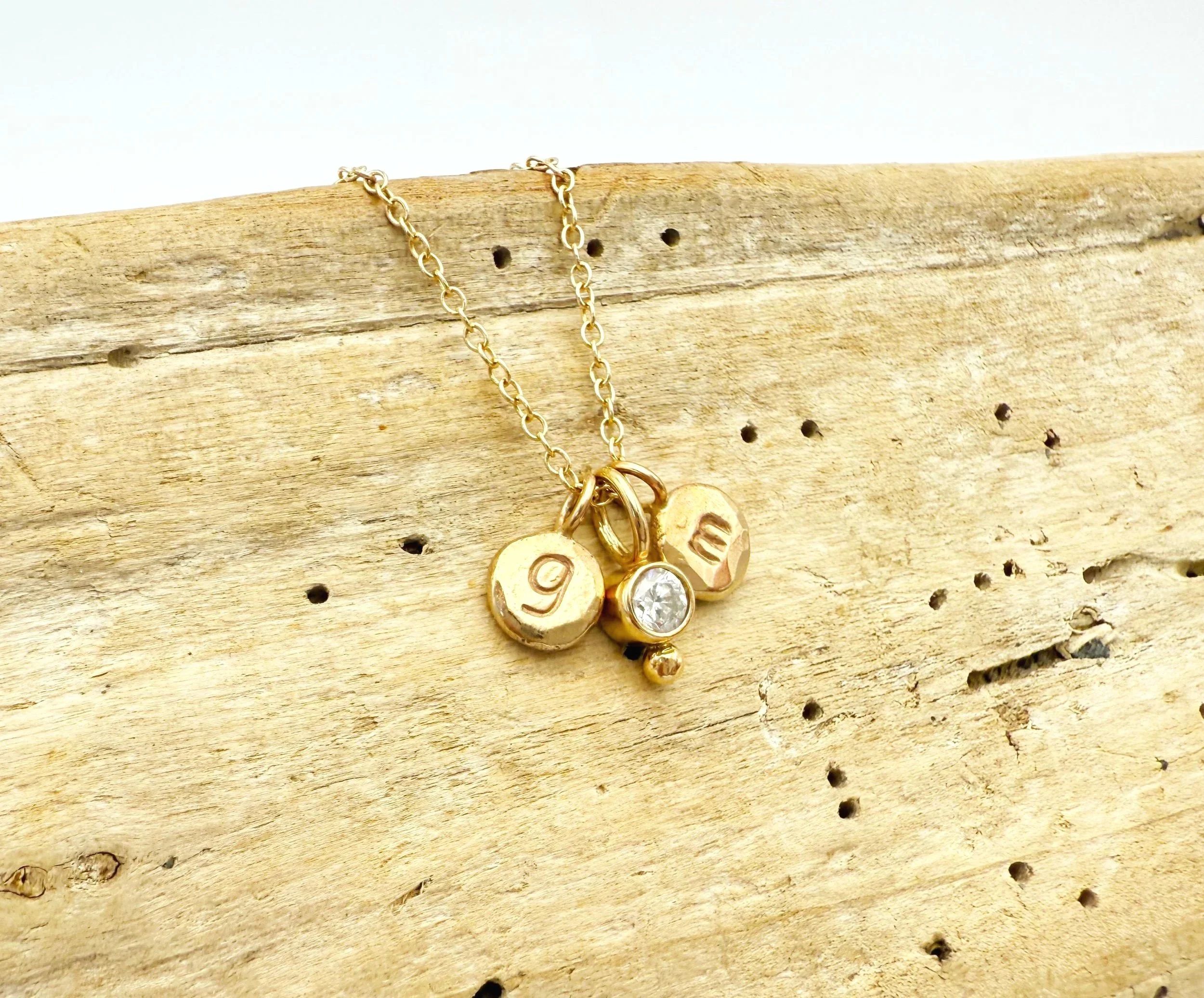 small disc necklace with stamped lower case initials in 14k gold