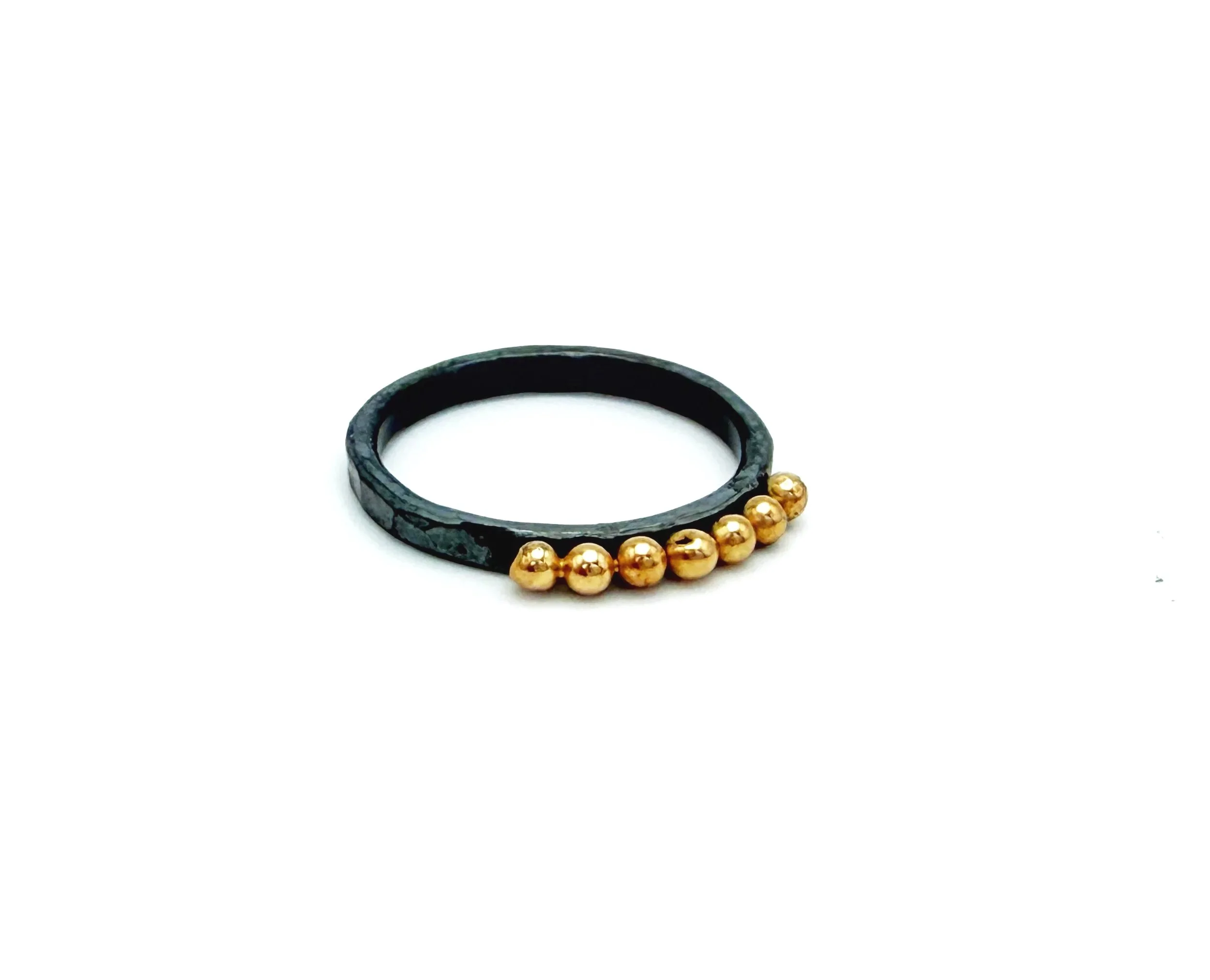 Oxidized sterling silver ring with seven polished 14k solid gold dots, on a white background