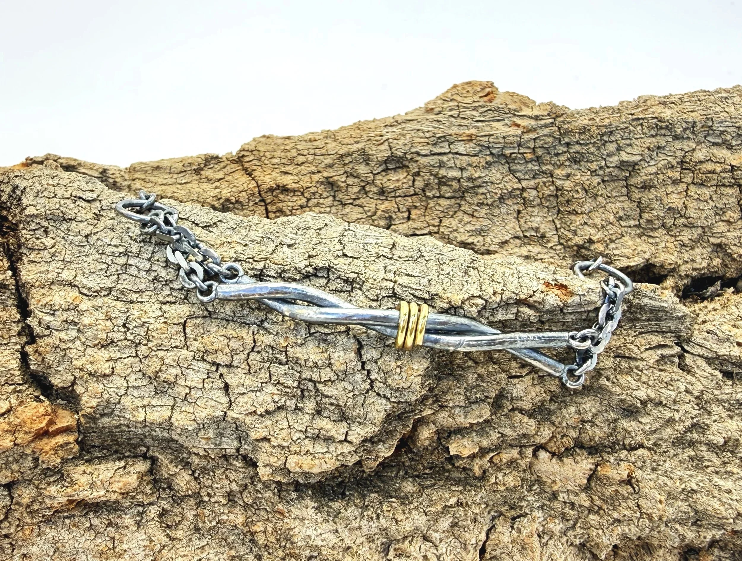 Oxidized silver and 14k gold twist bracelet on weathered stone