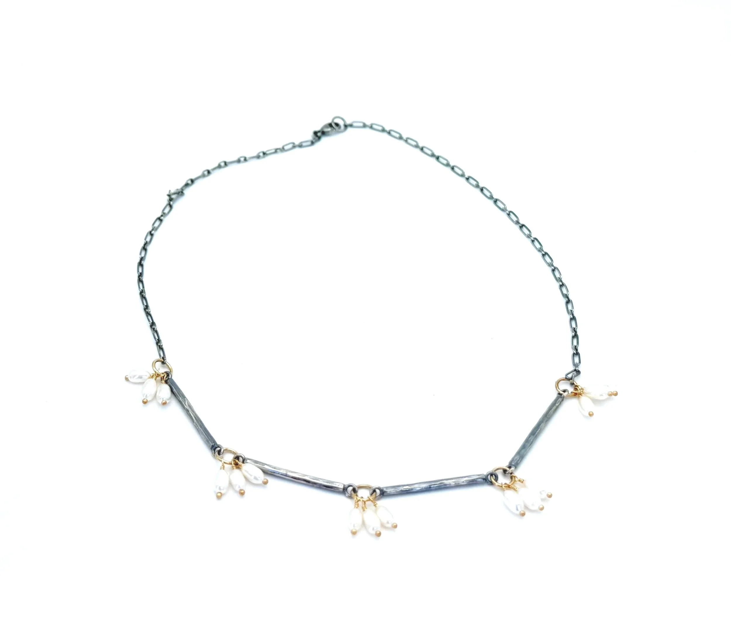 Freshwater pearl and silver bar necklace laid in a circle, on white