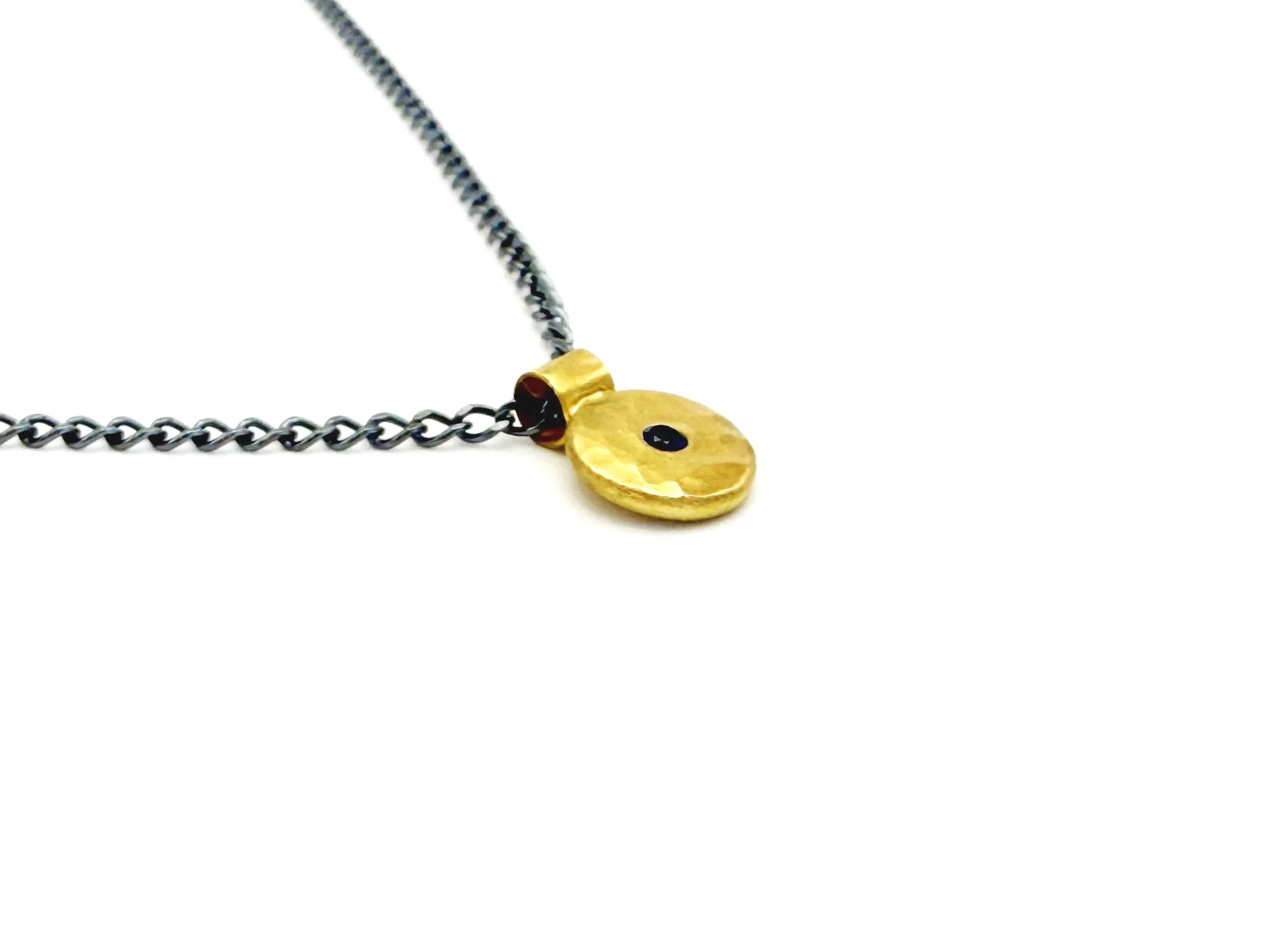Side view of the 18k gold disc pendant and bail on an oxidized chain, on white