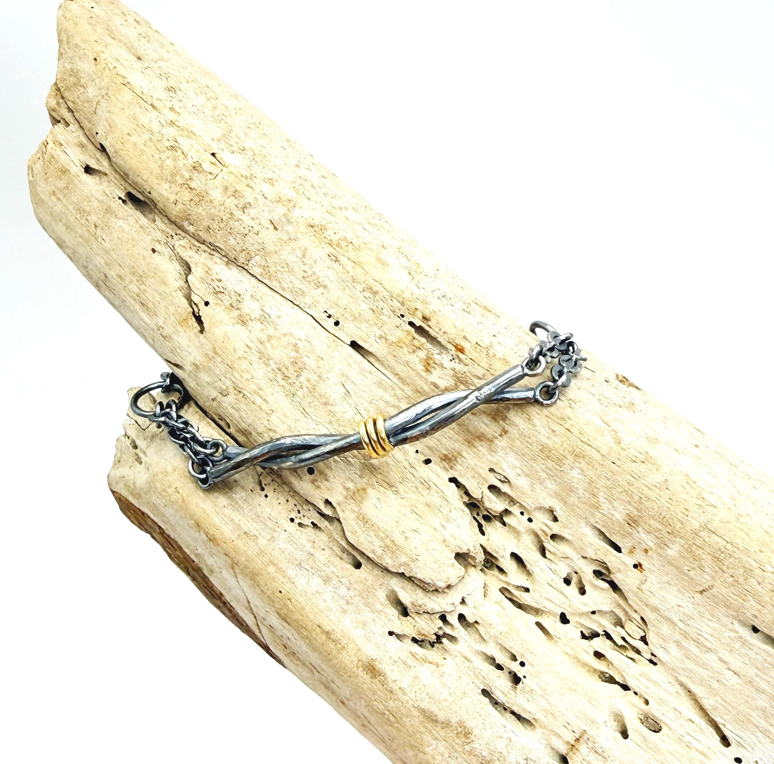 Twist bracelet laid diagonally across driftwood