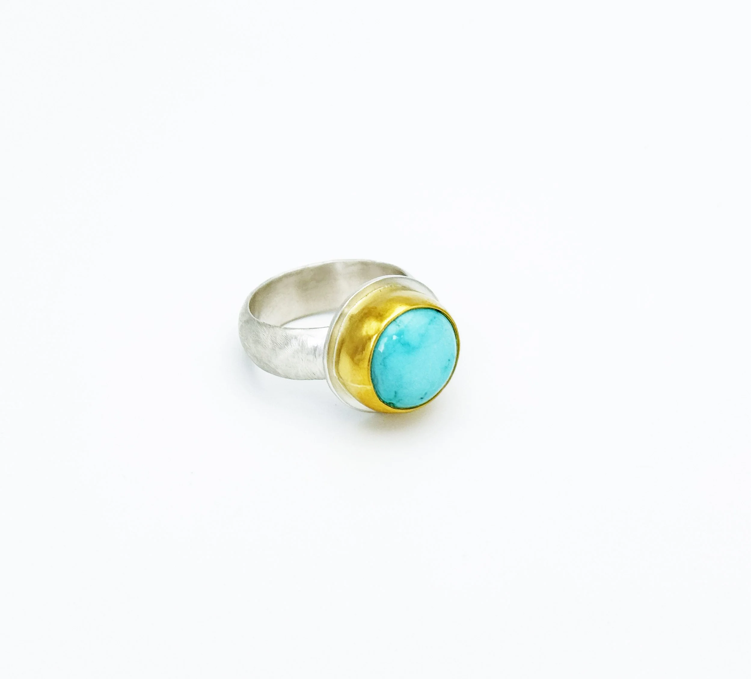 Round Fox turquoise ring in a 22k gold bezel on a sterling silver cigar band, on white