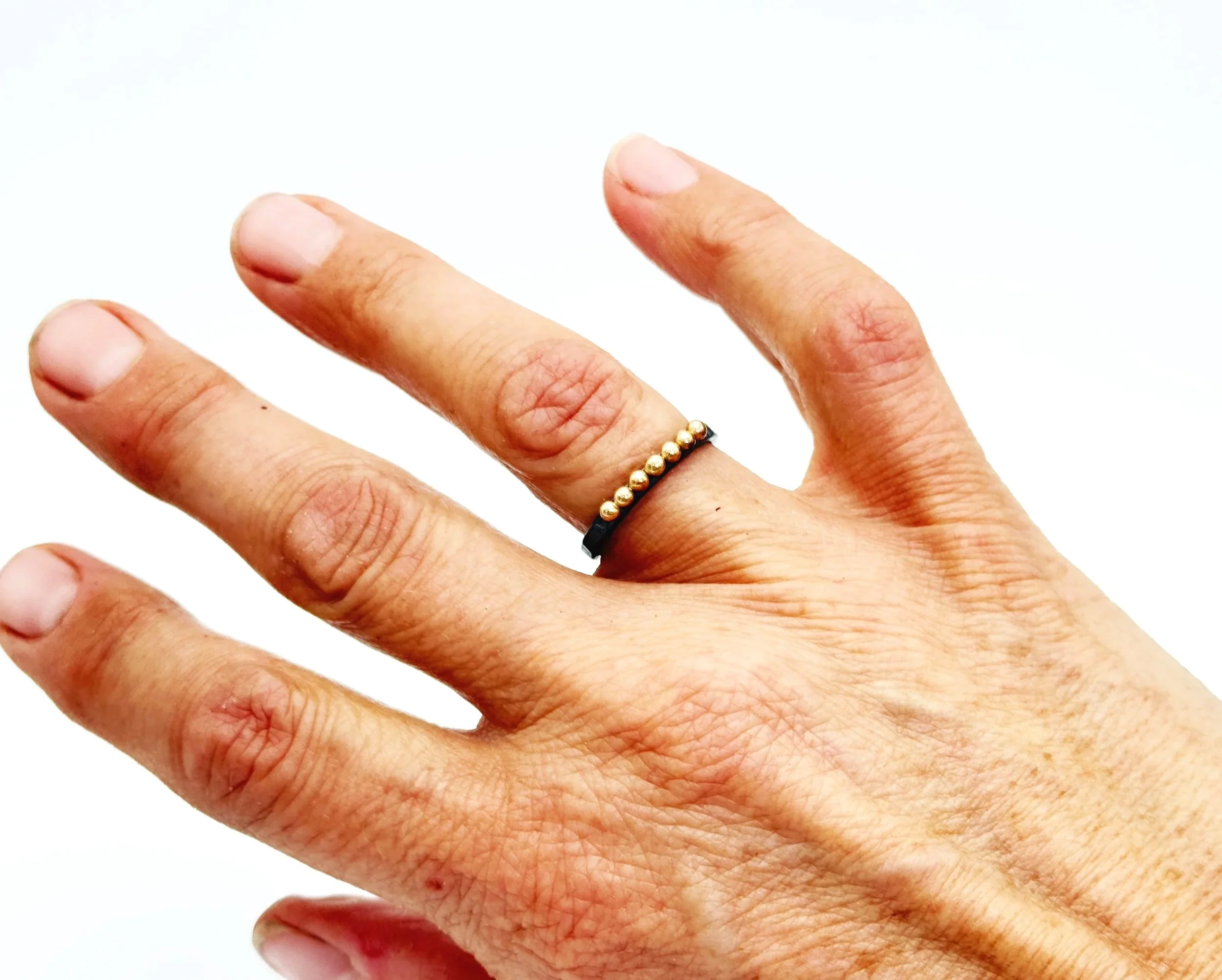 Oxidized silver ring with 14k gold dots worn on a hand