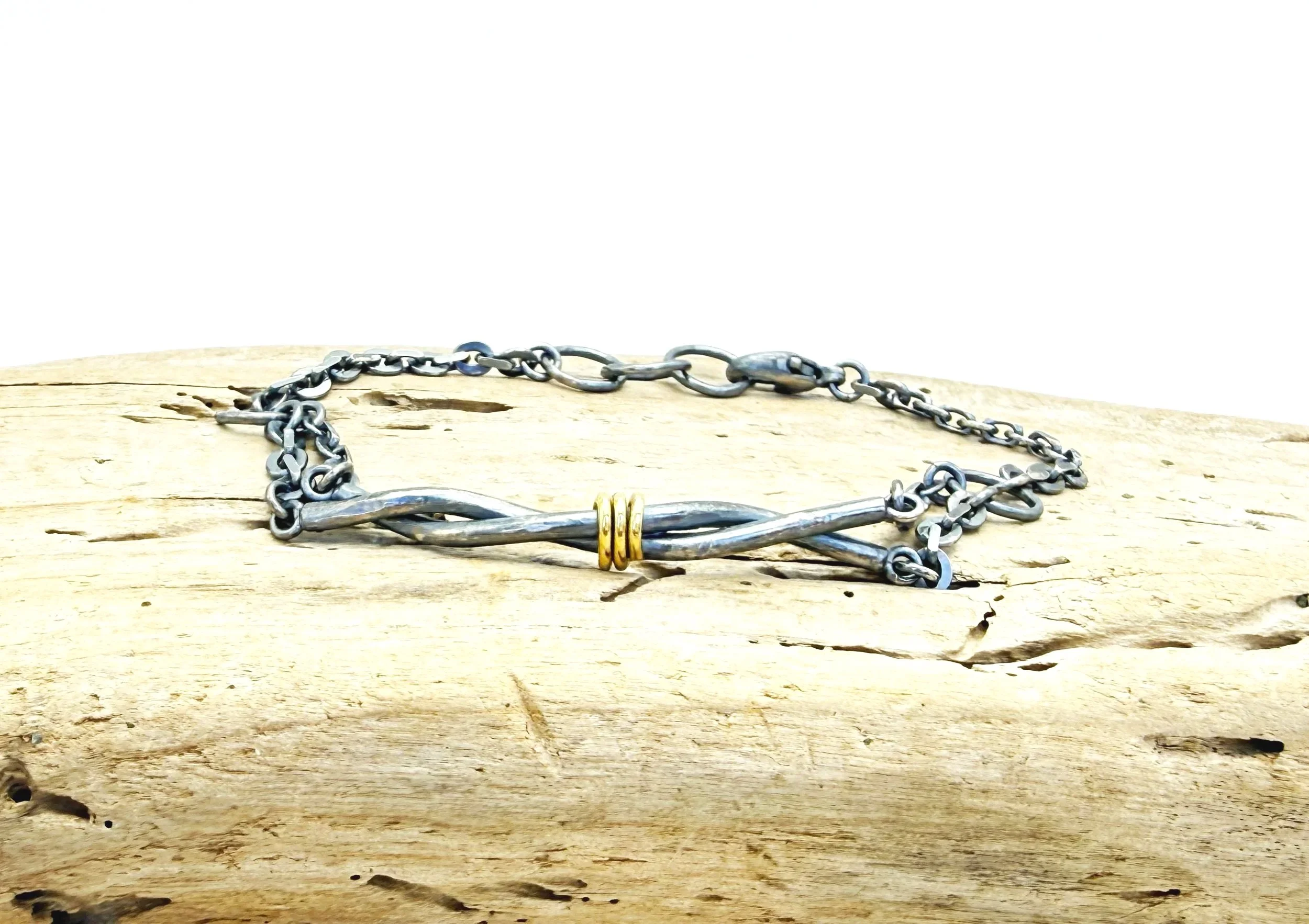 Twisted oxidized silver bars with 14k gold wrap on driftwood