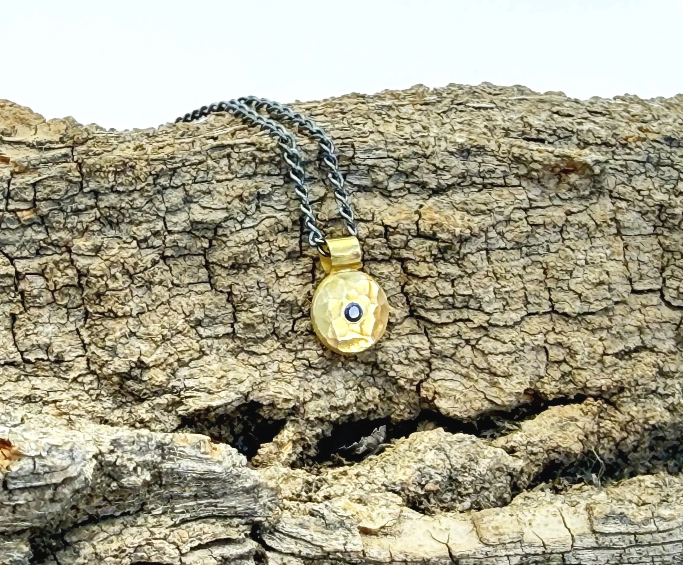 Solid 18k gold disc pendant with sapphire on weathered stone