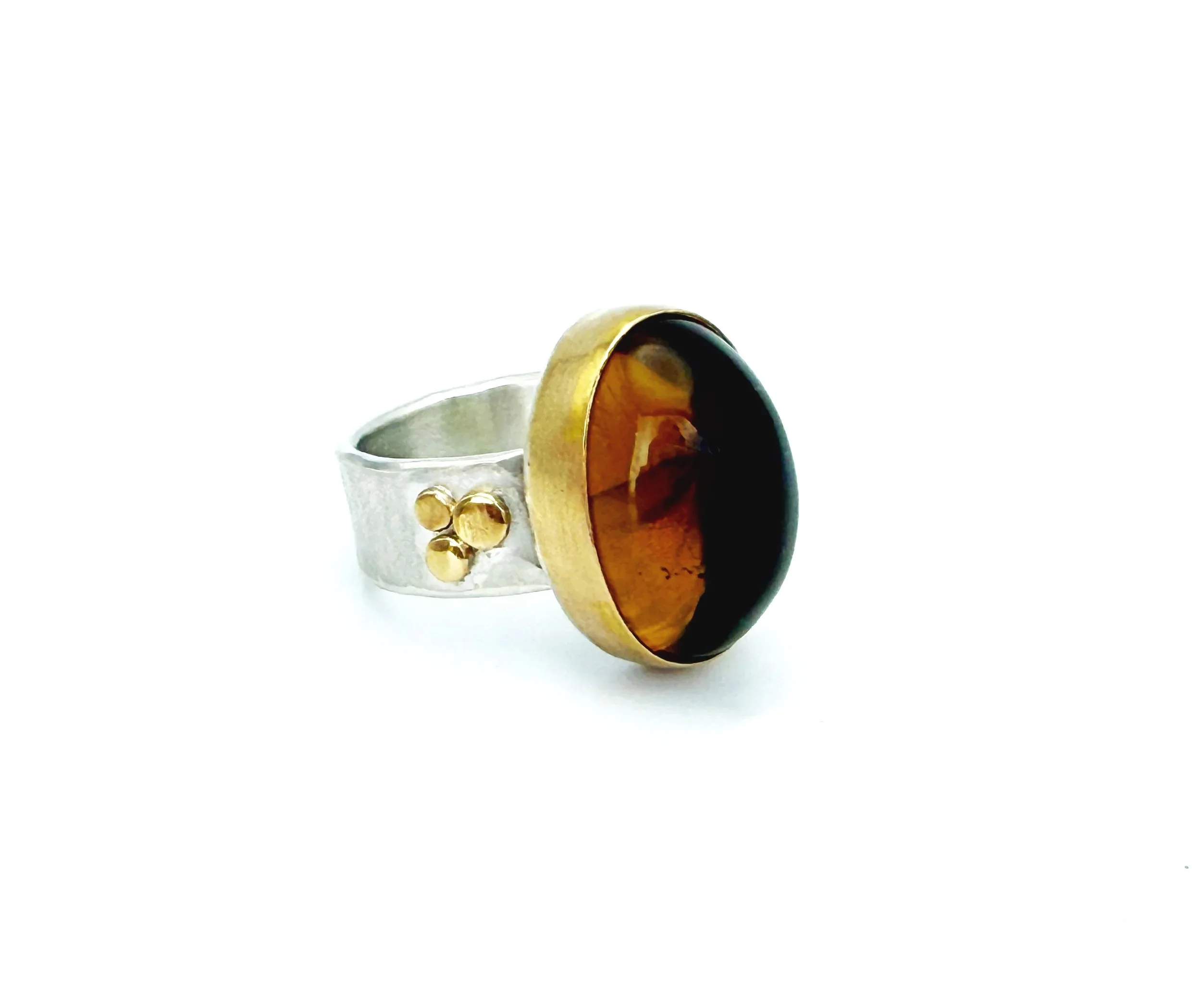 Honey-colored citrine cabochon in a 14k gold bezel with gold dots on the silver band, on white