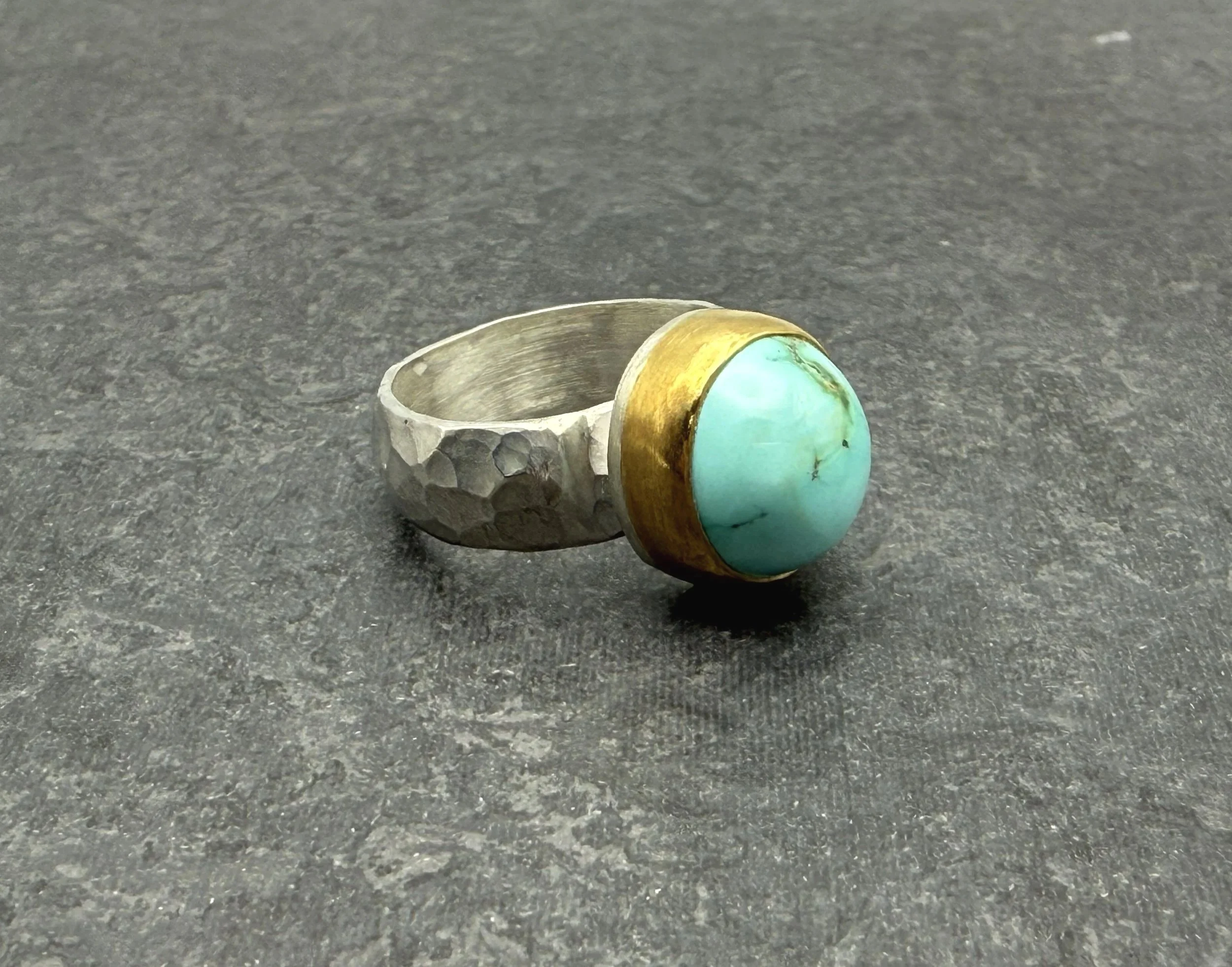 High domed blue turquoise stone in 22k gold bezel on a hammered silver cigar band