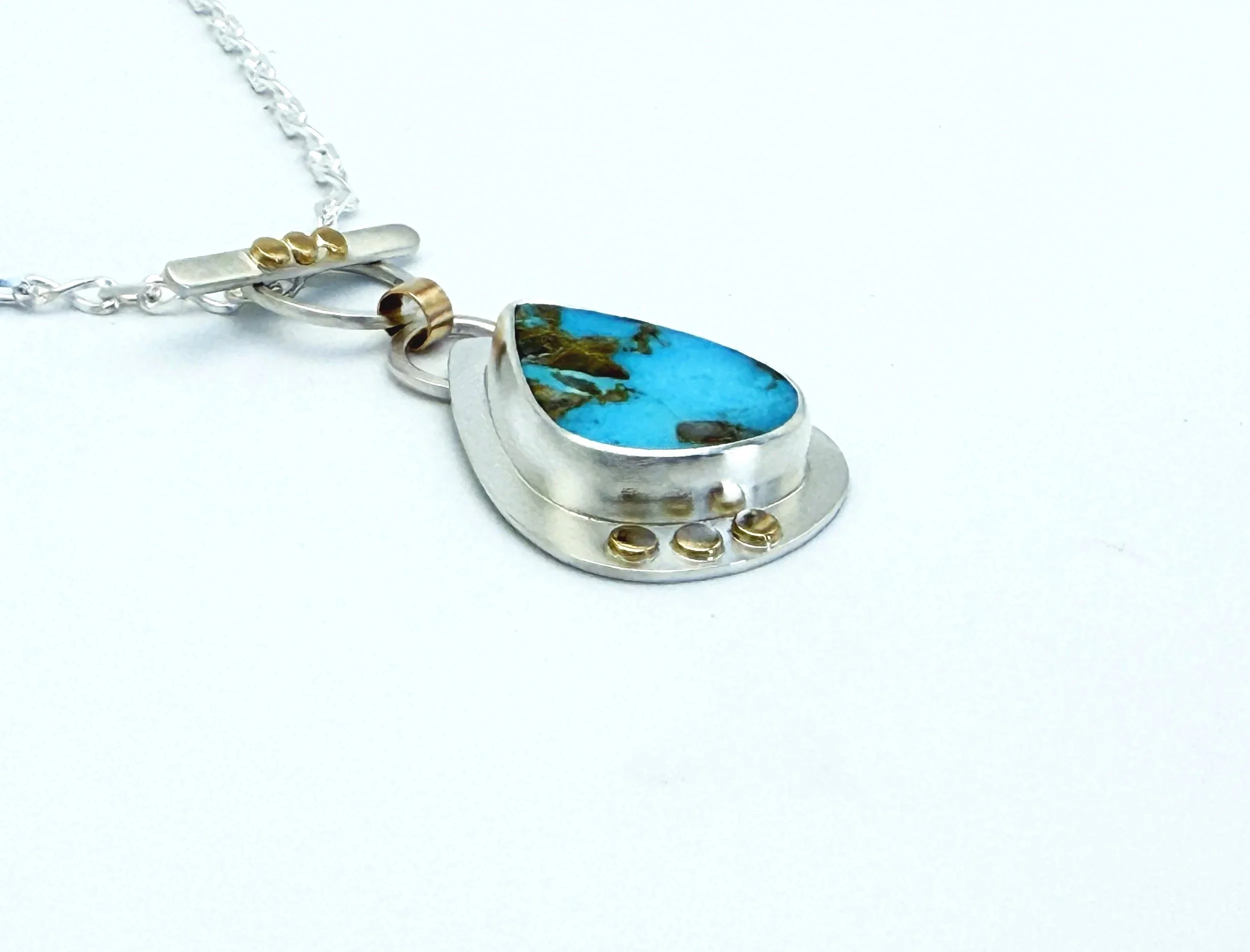 Side view of the Blue Gem turquoise pendant, showing the gold accents on the setting