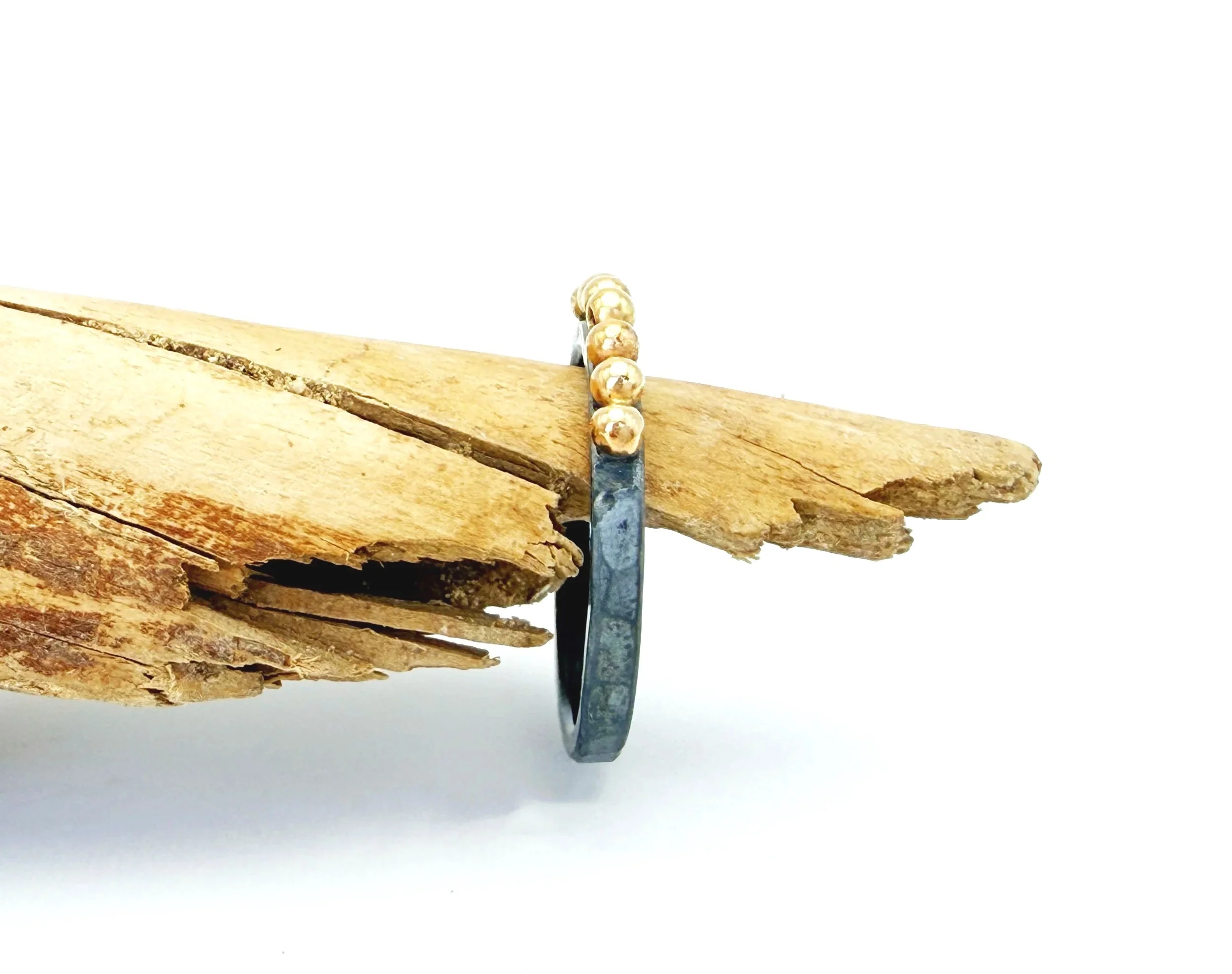 Side view of the oxidized silver ring on driftwood, showing the gold dots