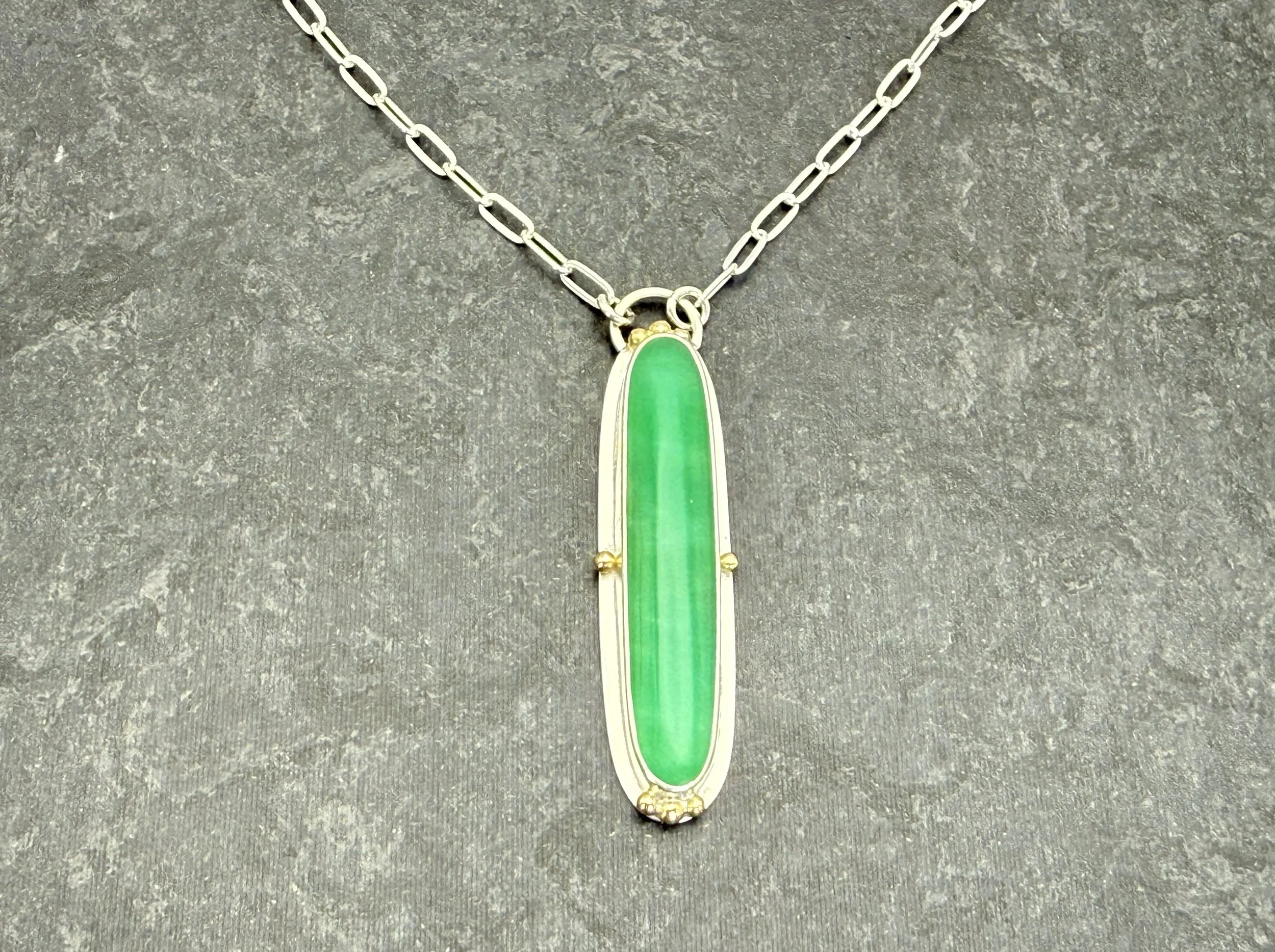 Long green chrysoprase pendant on a paperclip chain, on gray stone