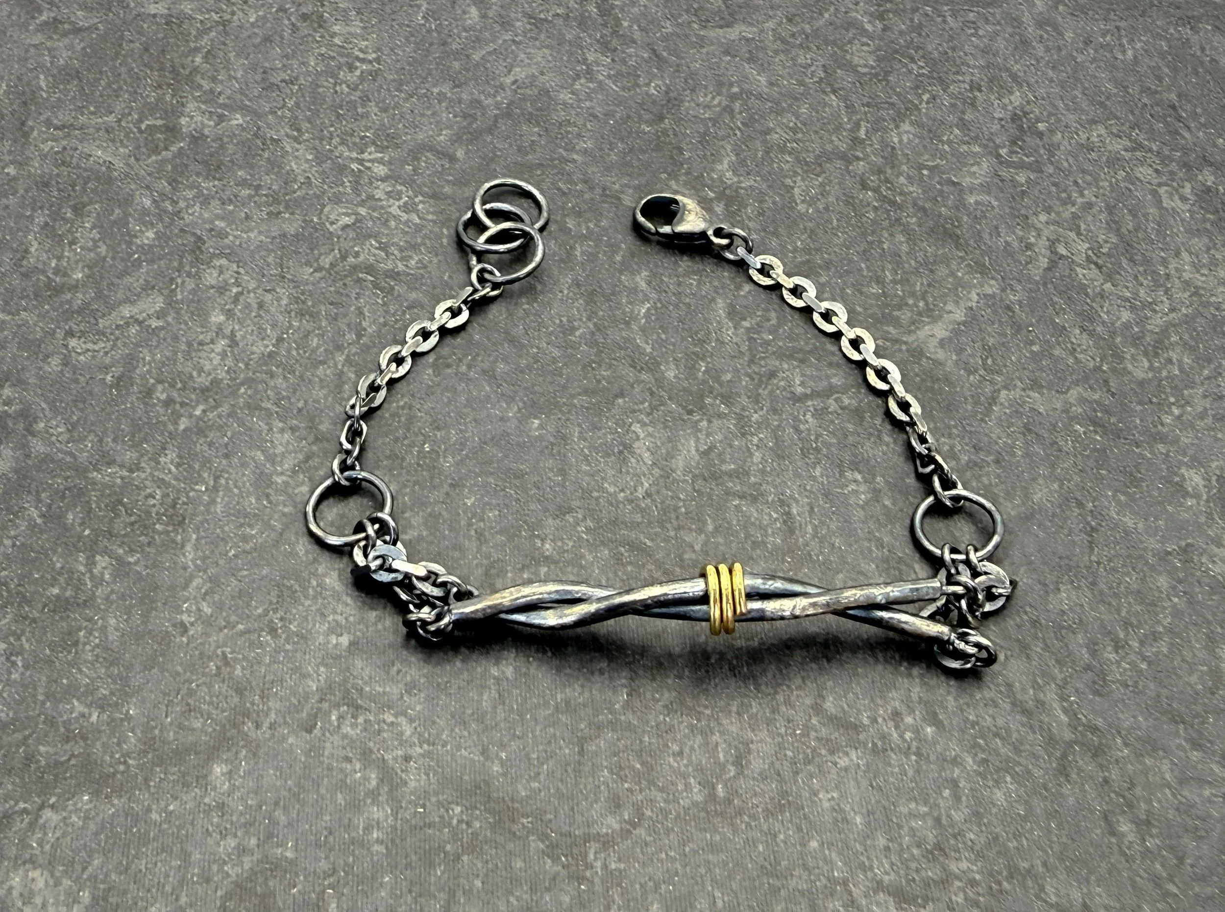 Silver twist bracelet with its chain and clasp on dark slate