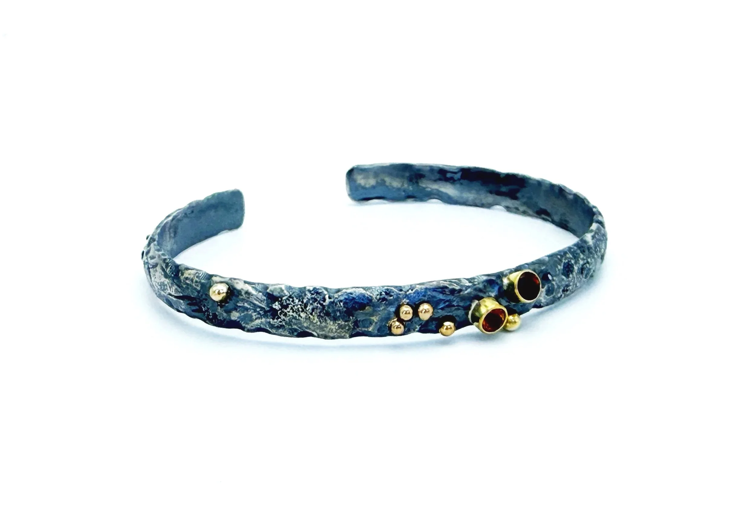 Oxidized silver cuff bracelet with scattered 14k gold dots, on white