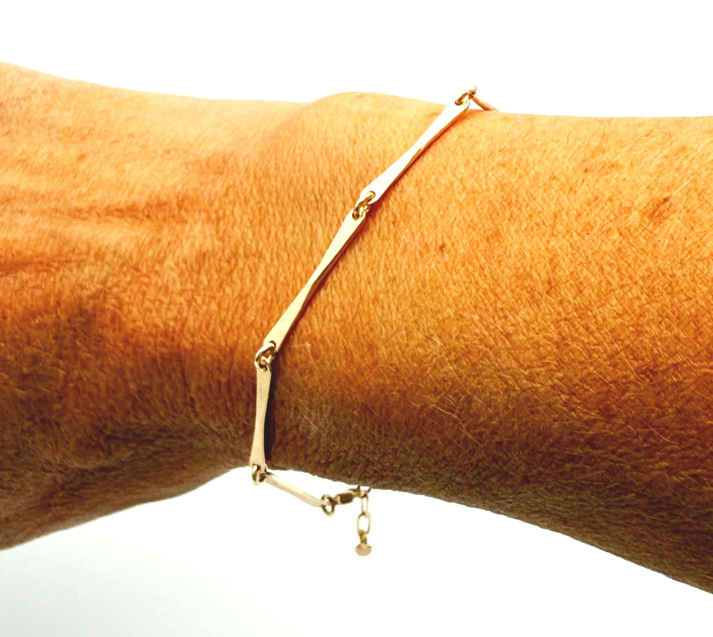 Bar link bracelet in 14k gold shown worn on wrist