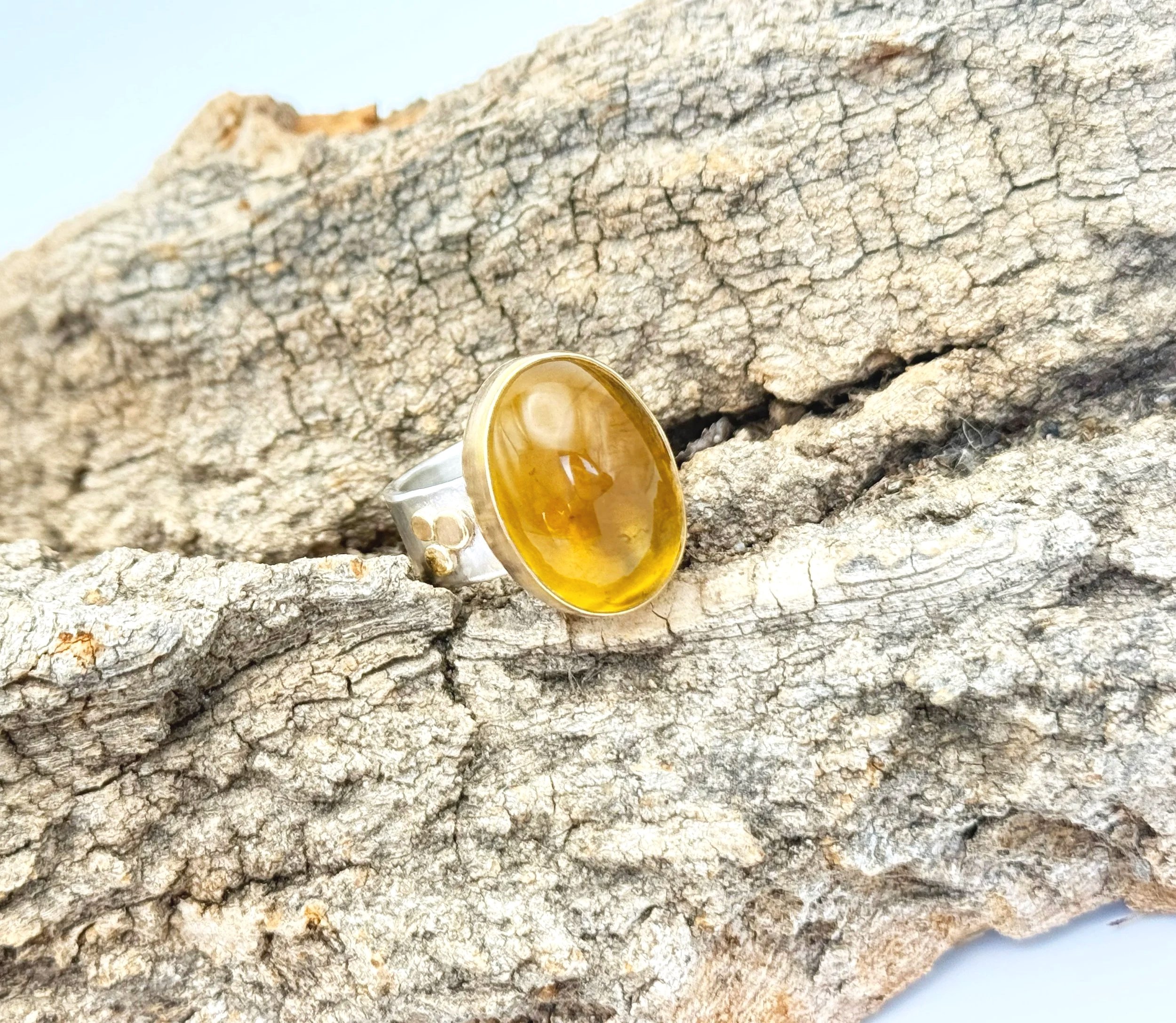 Large oval citrine ring in a 14k gold bezel on a hammered silver band, on stone