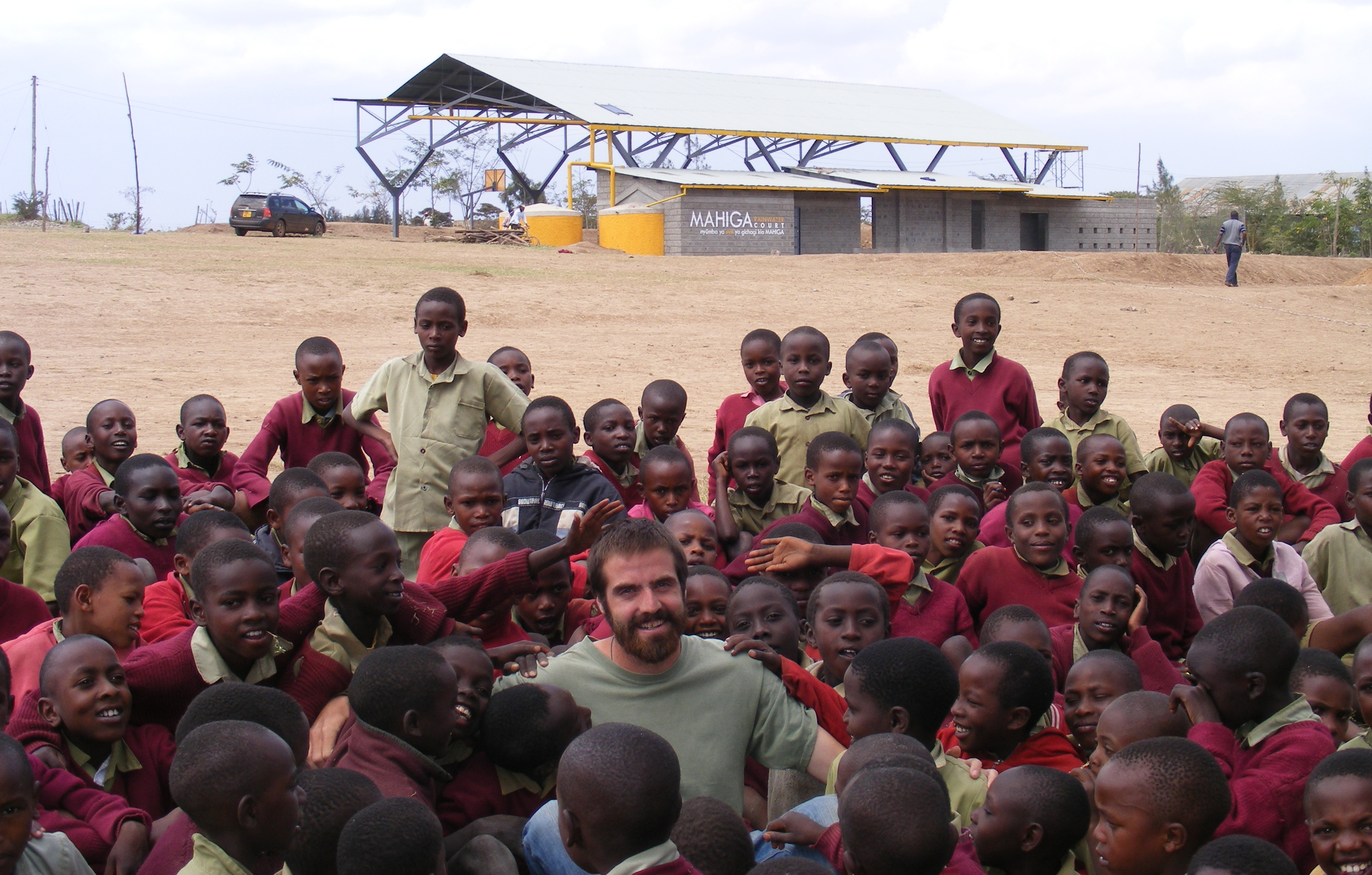 Greg is surrounded by a mob of children in front of the recently constructed Mahiga Rainwater Court (2010)