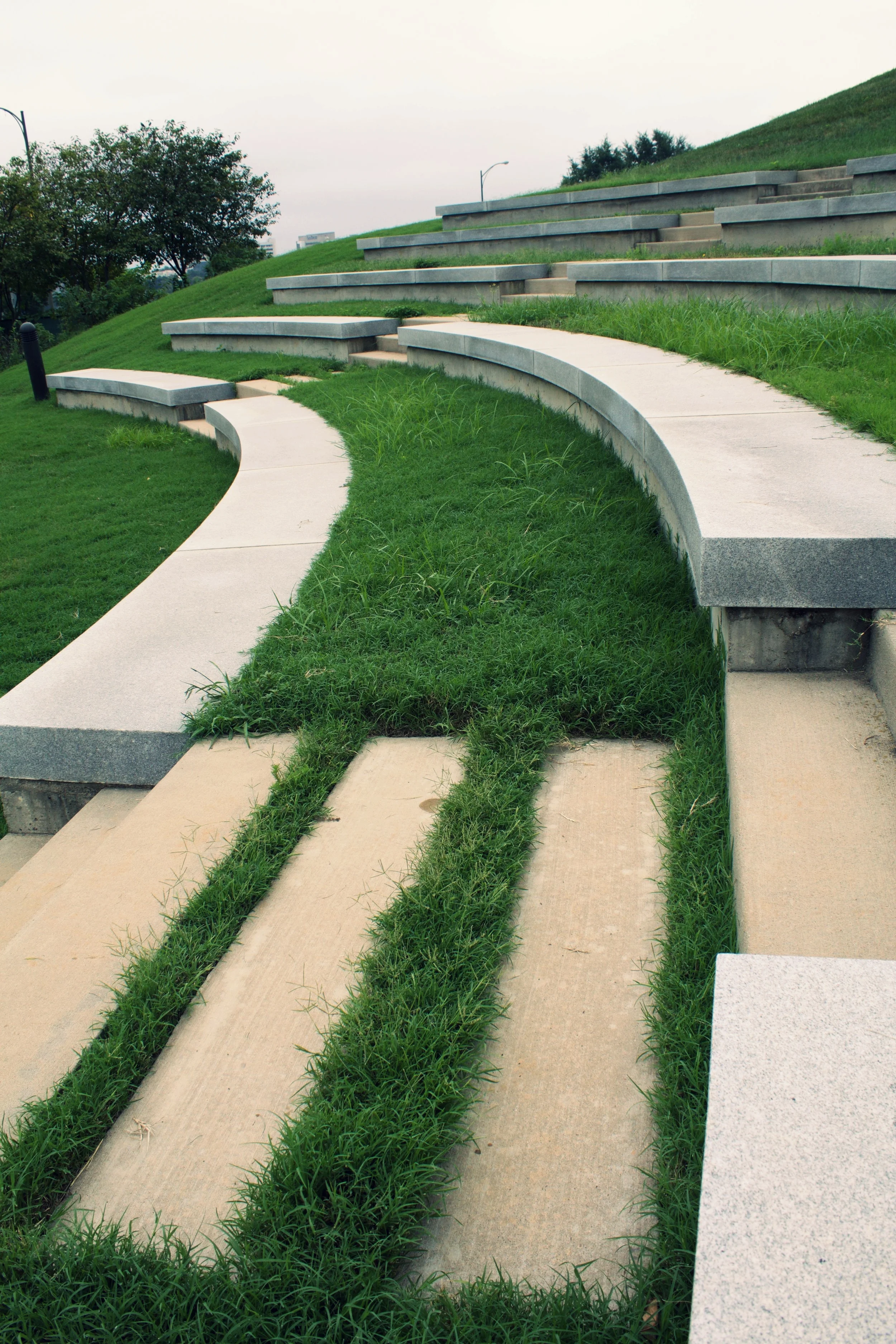 The different stone seats separated from the steps both in color and material, creates for a subtle suggestion of where to stay and where to walk. The width of the seats are generous to complement the Shrine once again, and the softness of the grass…