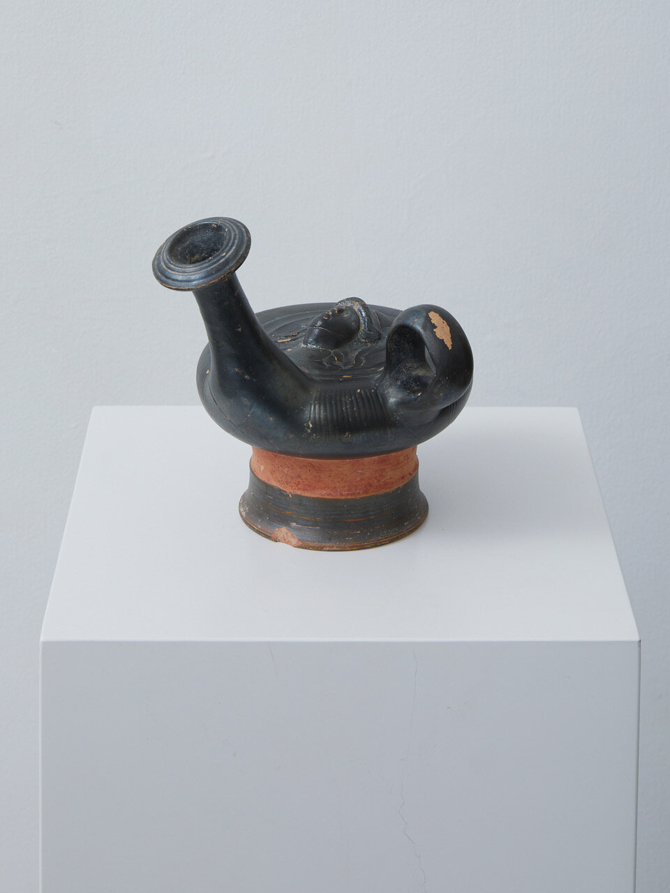 Apulian Black-Glazed Guttus Hellenistic period, 2nd half of the 4th century BC, Western Greek, Apulia 130 x 140 x 155mm Provenance: Private collection, West Germany. Apulian black-glazed guttus made from toned clay with ribbed body and ring handl