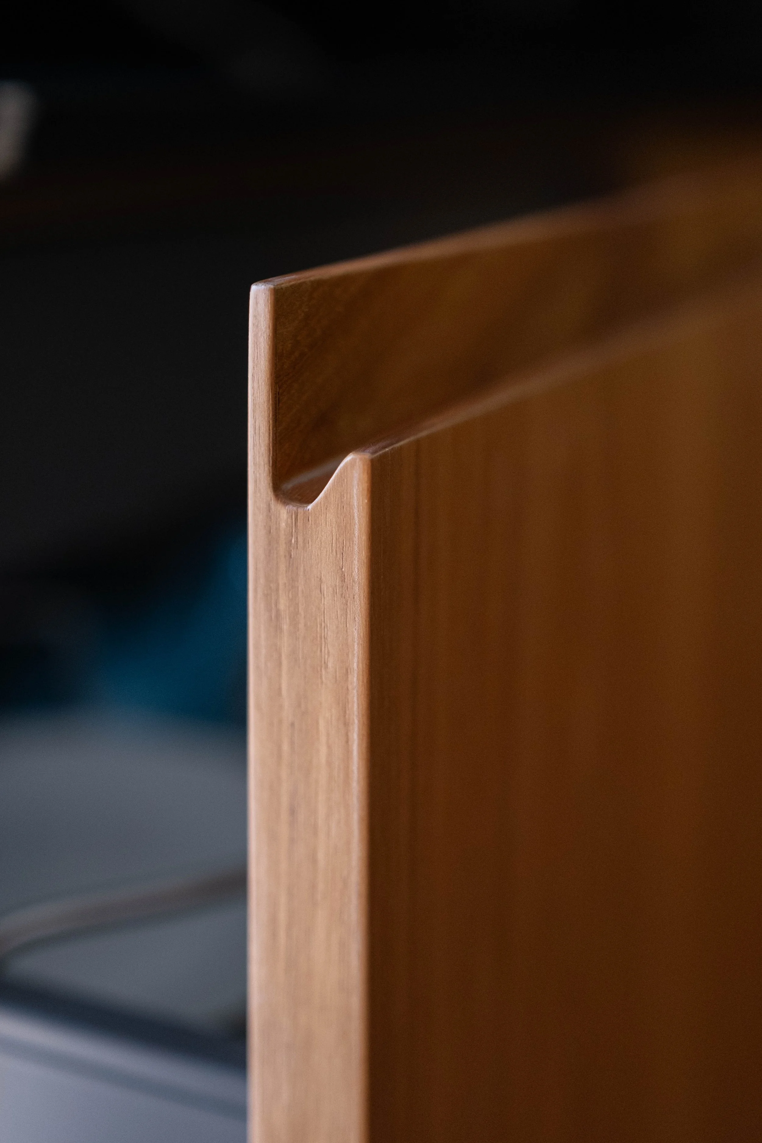 Close-up of the corner of a wooden furniture piece, focusing on the mitered edge and smooth finish with a dark background.