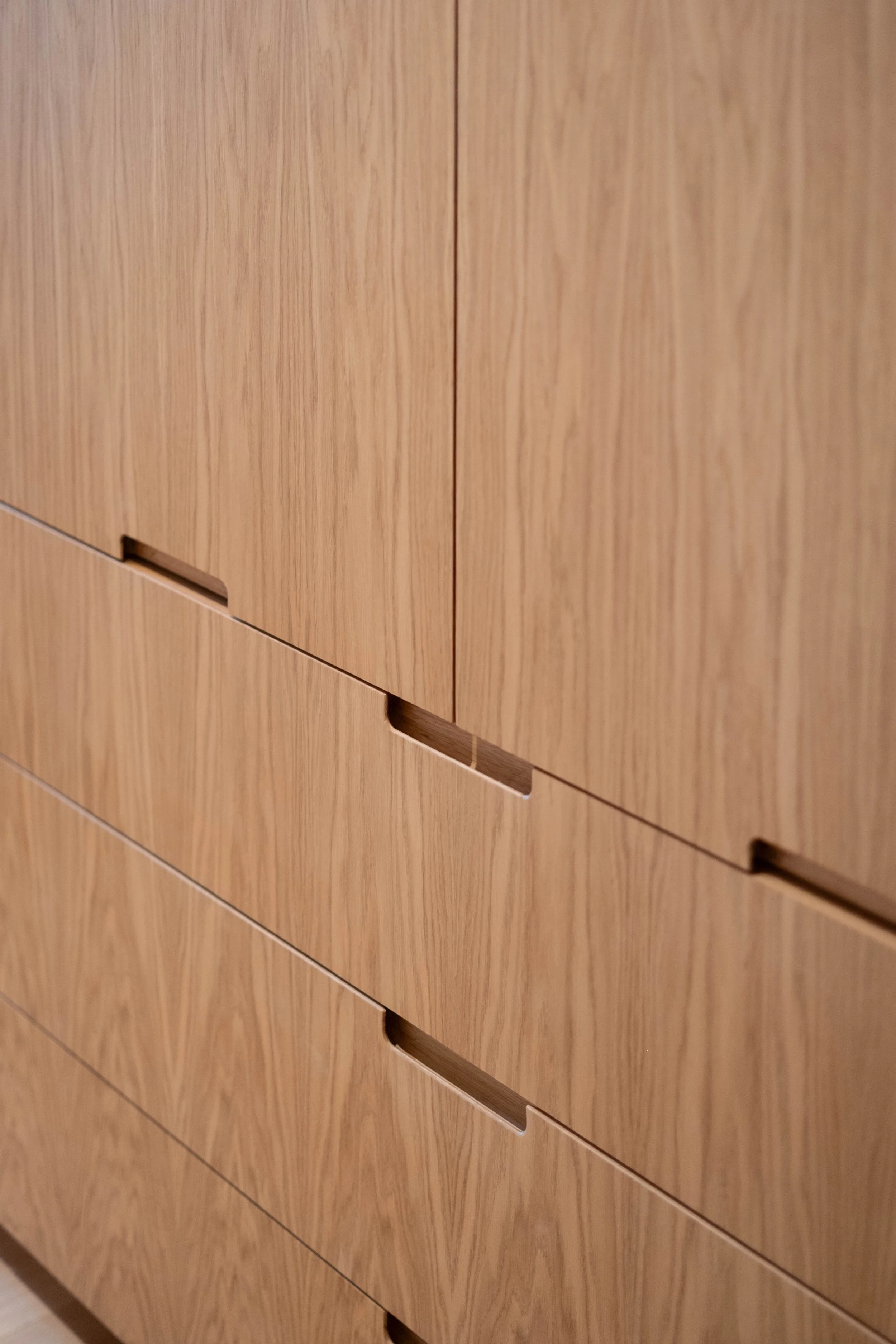 Close-up of wooden cabinet drawers with horizontal handle slots.