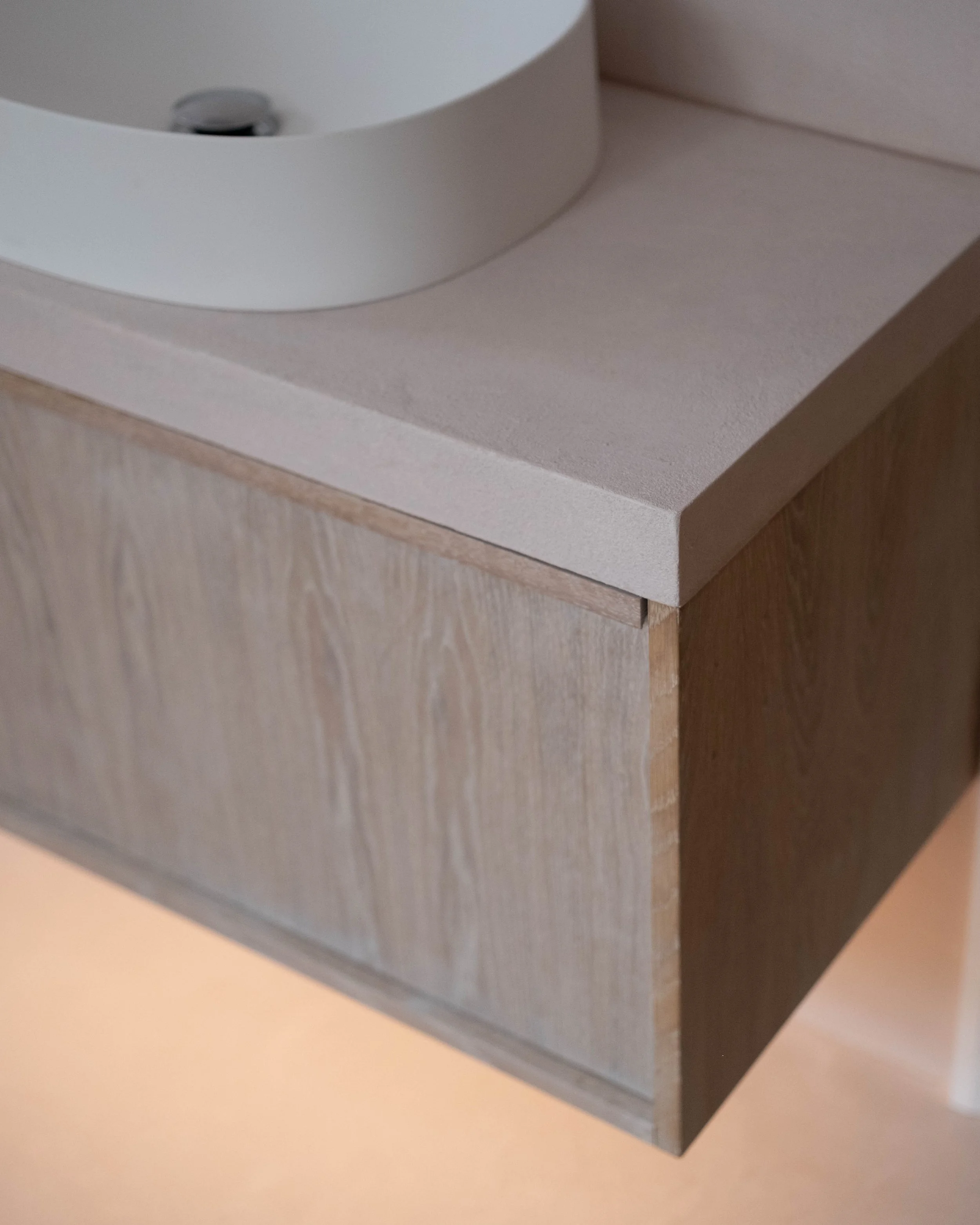 Close-up of a modern, minimalist beige and dark brown wooden cabinet or dresser with a white top surface.
