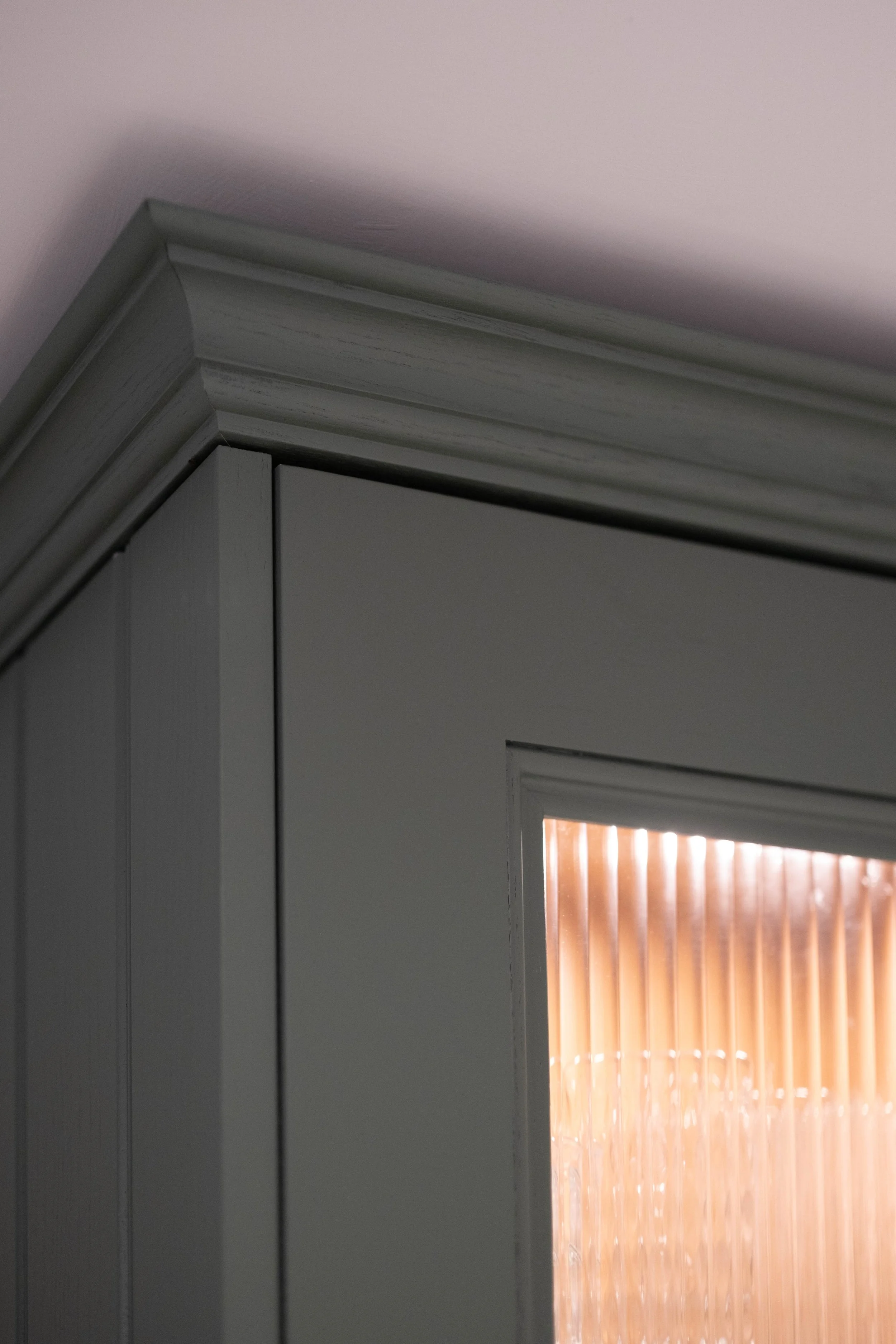 Close-up of a white wooden doorframe with a window that has vertical blinds, partially open, revealing a hint of sunlight outside.