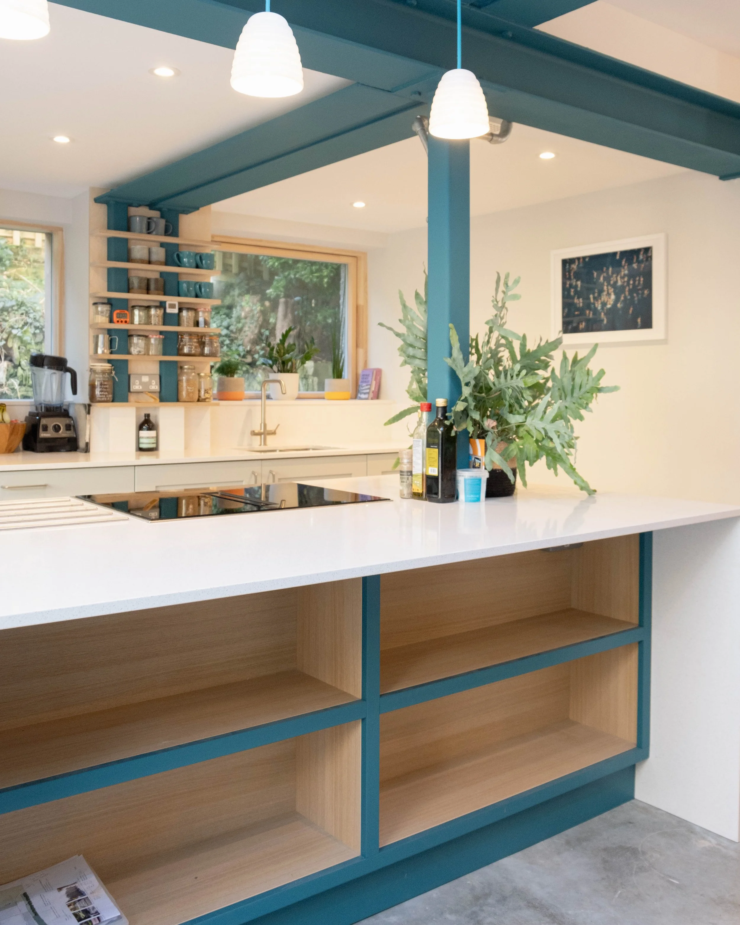Unfinished kitchen island with a white countertop, blue trim, open shelves, and a plant on the countertop.