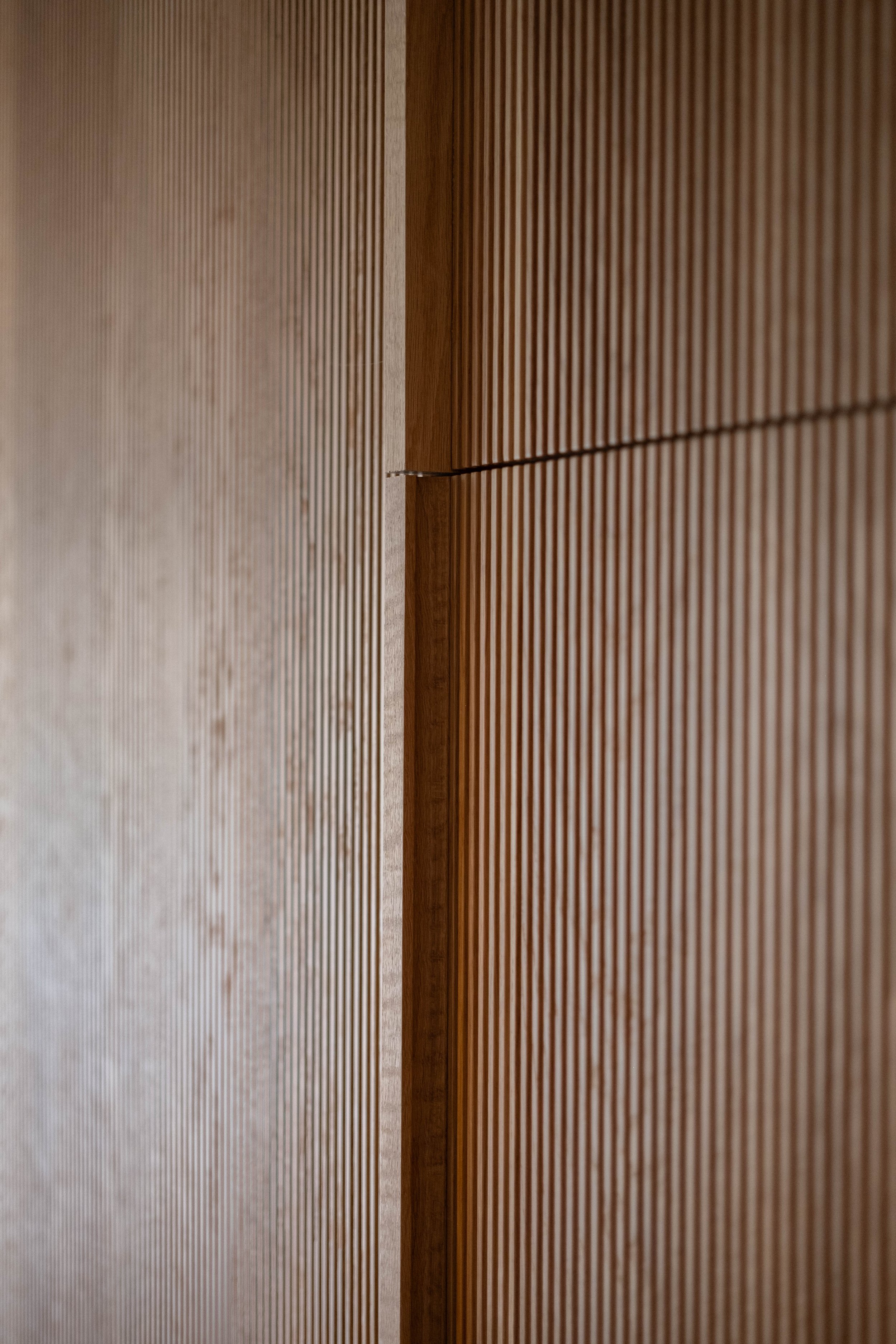 Close-up of wooden slats on a wall or partition with a narrow gap between two sections.