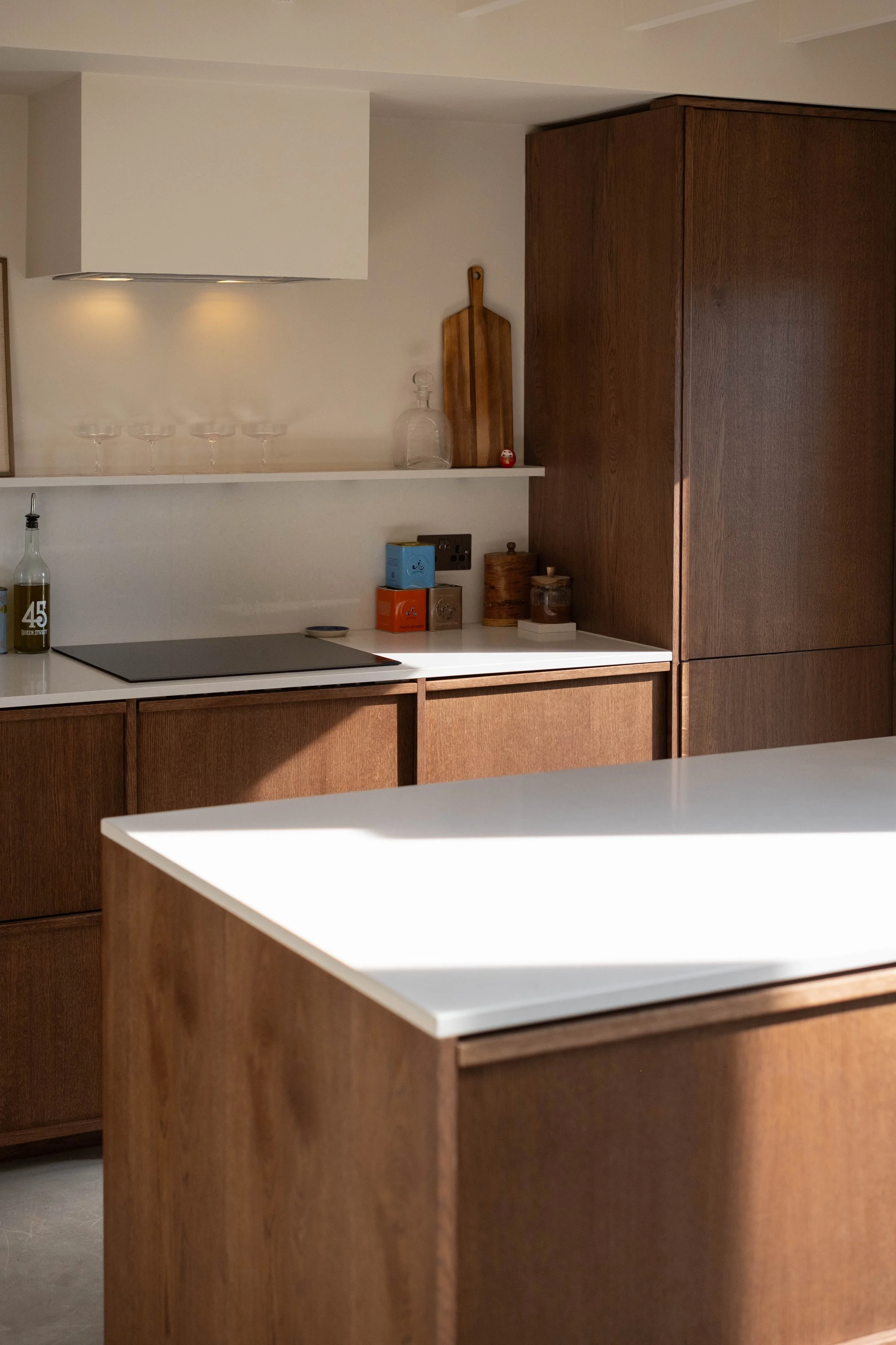 A modern kitchen with wooden cabinets, a white countertop, and a variety of small kitchen items on the counter.