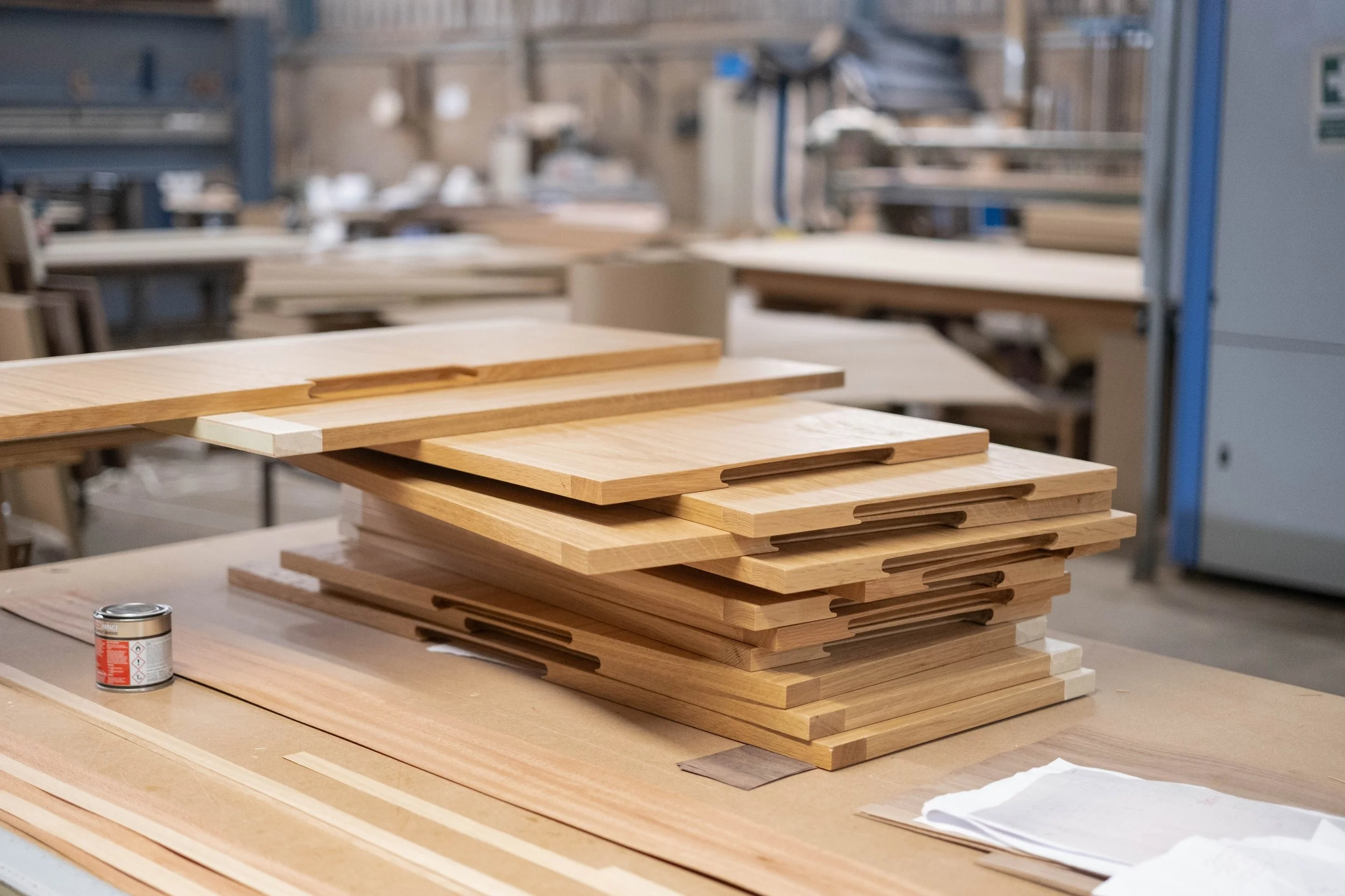 Wooden boards stacked on a workbench in a woodworking shop.