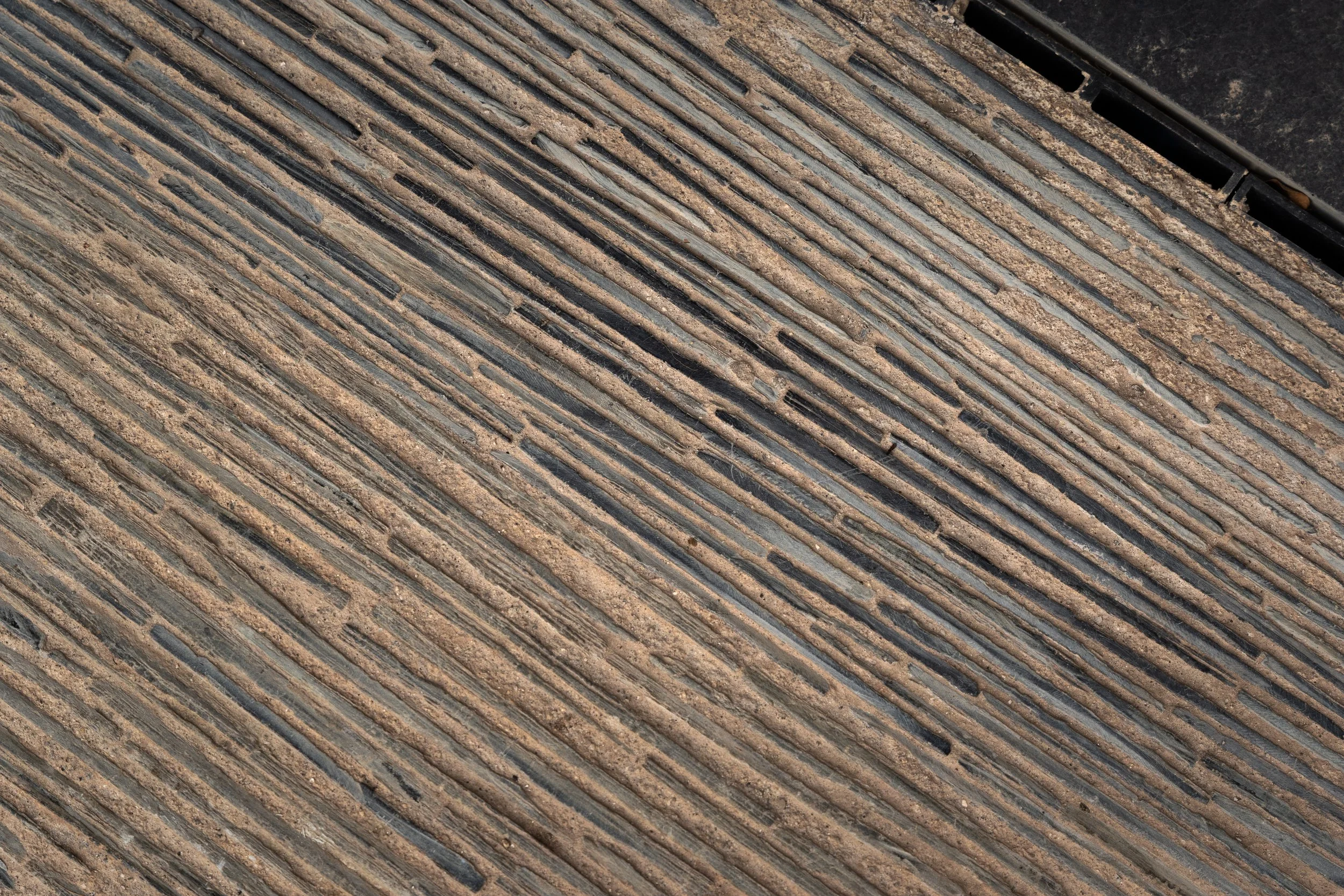 Close-up of a doormat with parallel ridges and grooves, dirt and dust accumulated in the grooves.