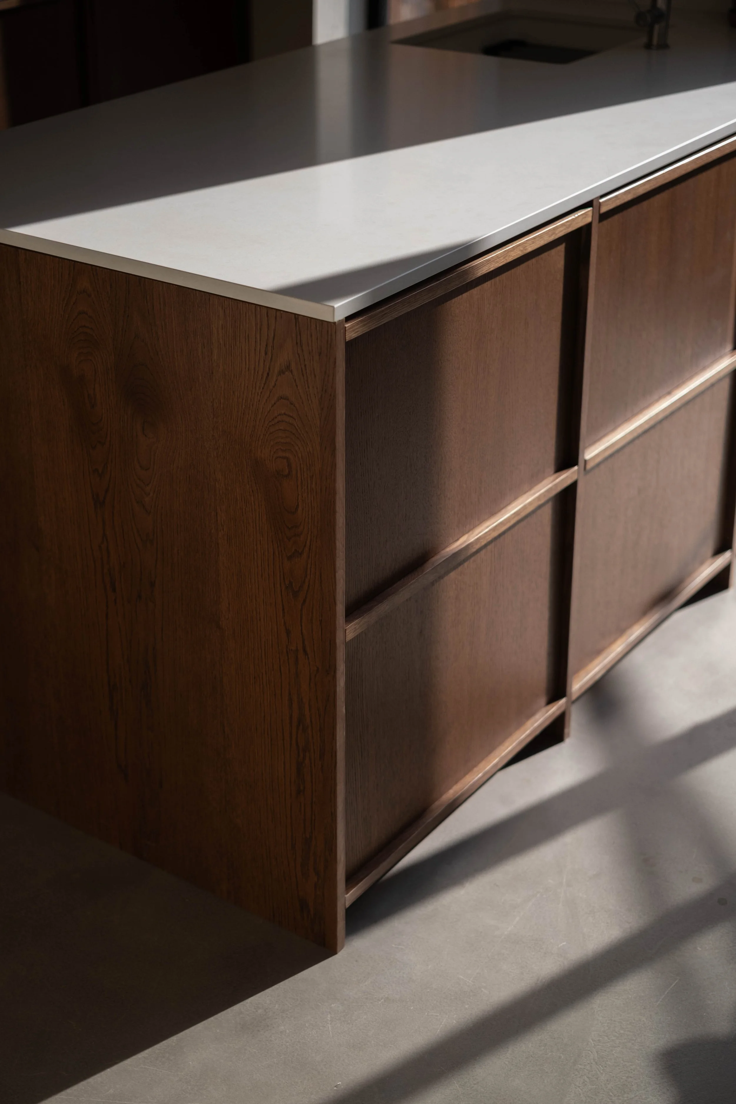 A wooden cabinet with a light-colored countertop and shadowed area on the surface. The cabinet has a rectangular shape with multiple compartments.