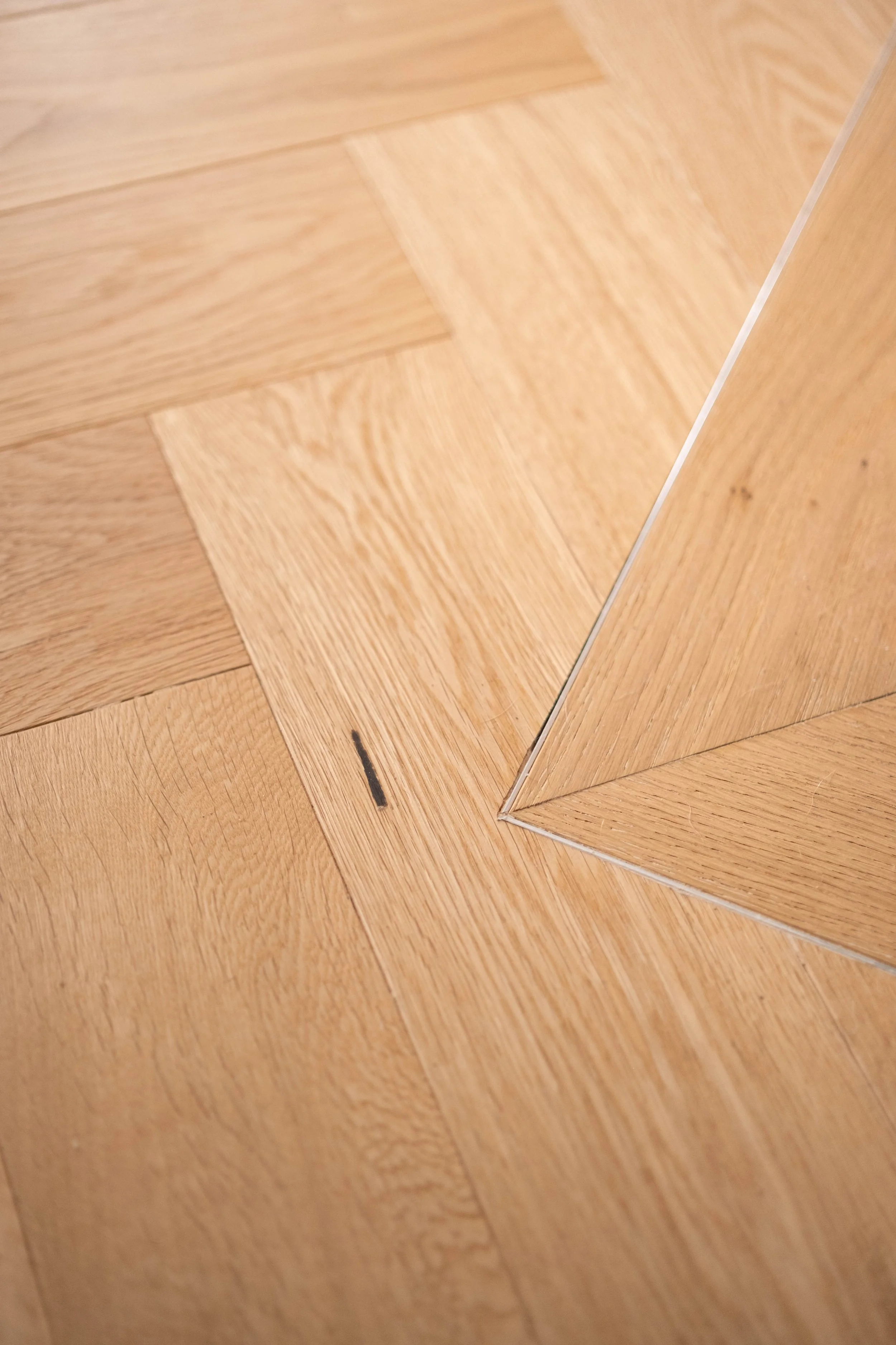 Close-up of wooden flooring with a mirrored surface reflecting the wood pattern.
