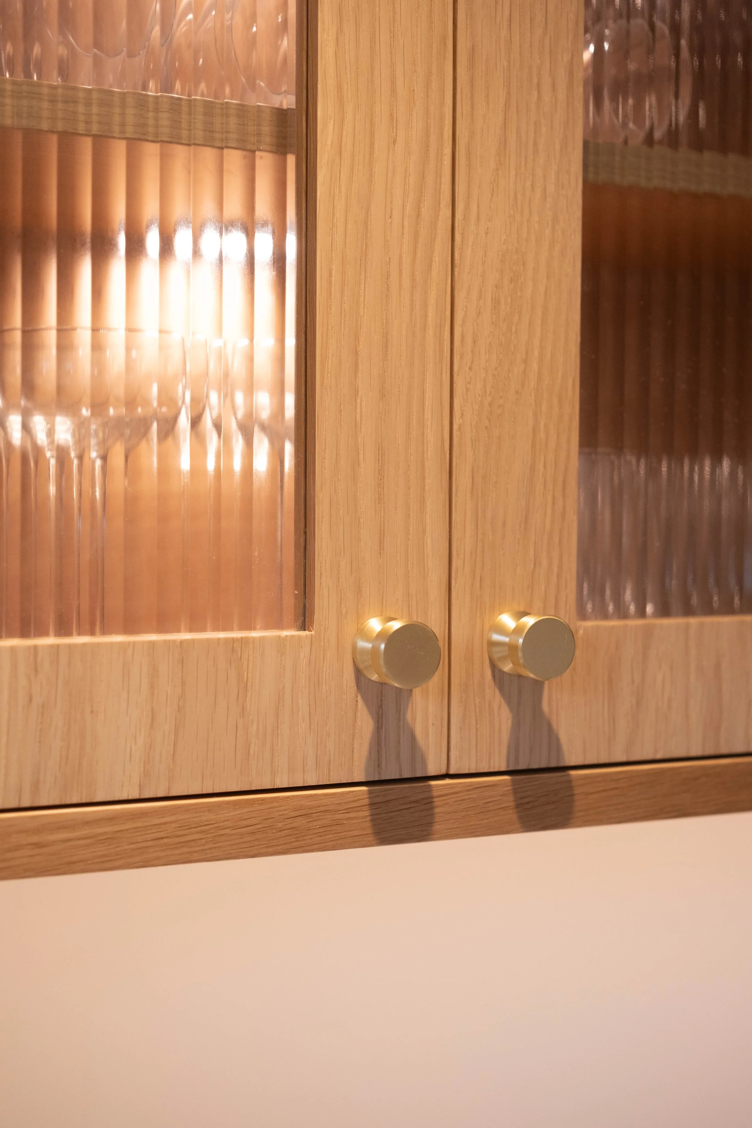 Wooden cabinet with glass panel doors and round golden knobs.