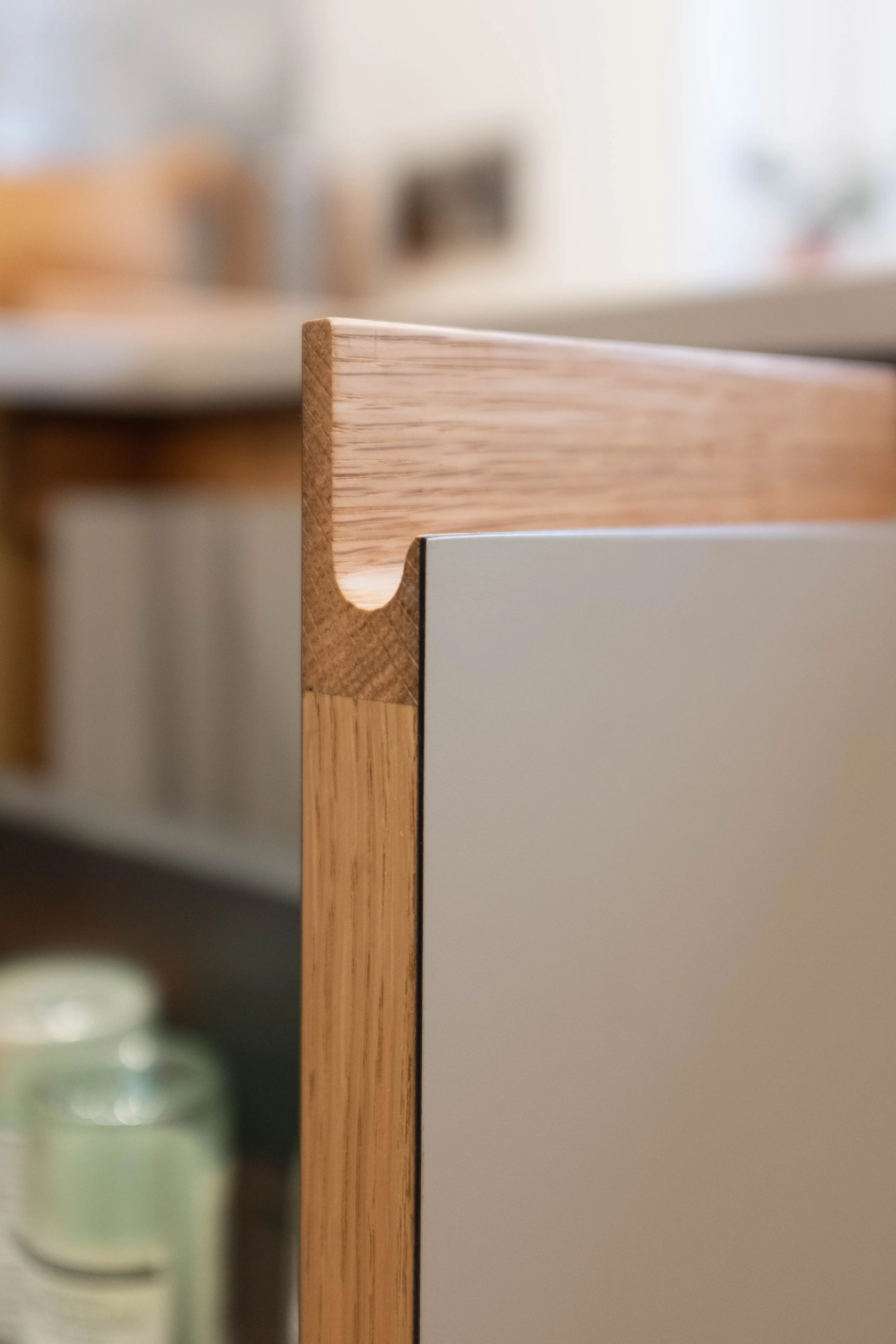 Close-up view of a wooden furniture corner, with the background blurred showing a light-colored room.