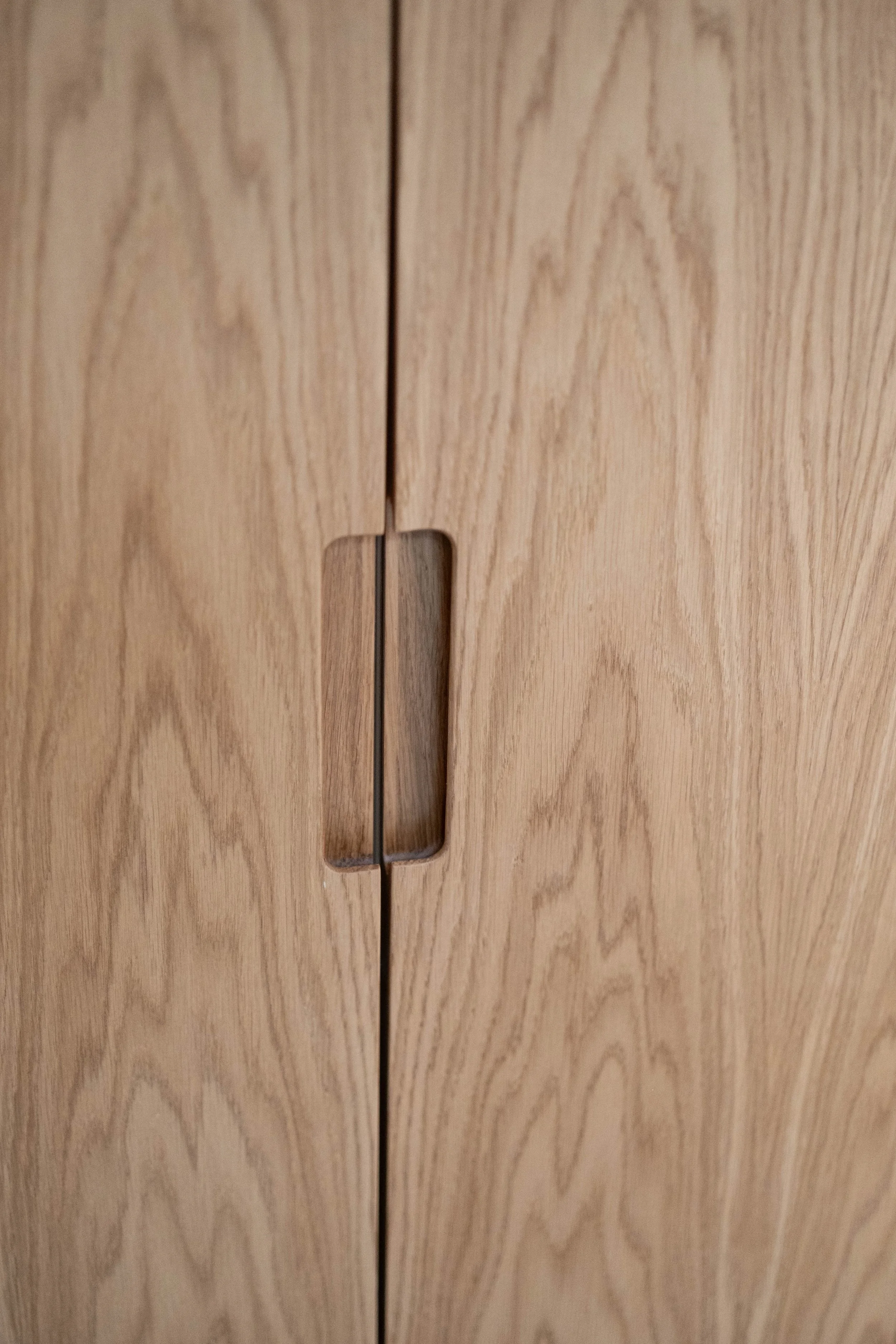 Close-up of a wooden cabinet with a rectangular slot or handle in the middle.