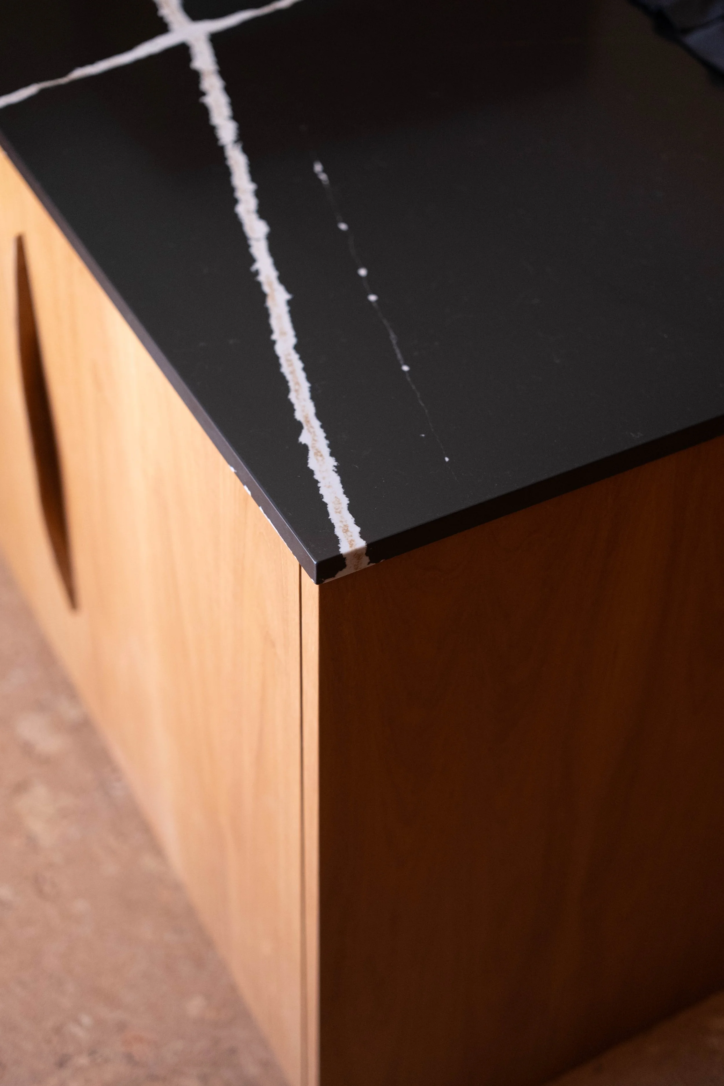 Close-up of a black table with white chalk marks and scratches, adjacent to wooden furniture.