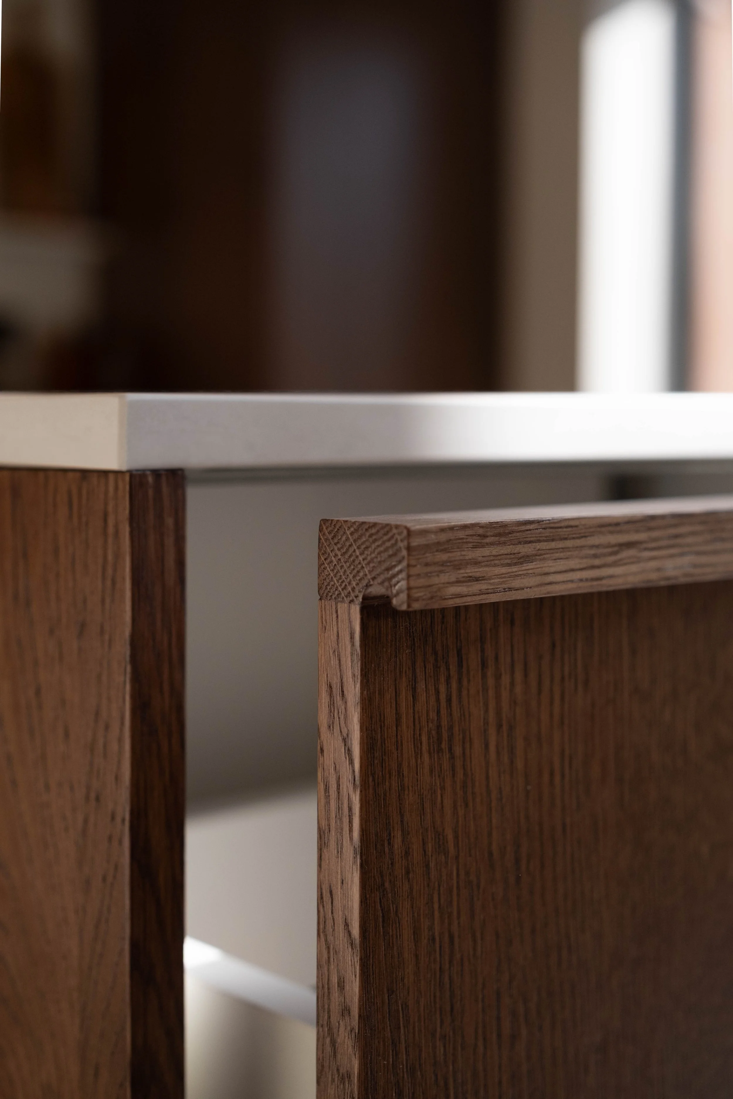 Close-up of two wooden furniture pieces, one darker and the other lighter, with a white surface in the background.
