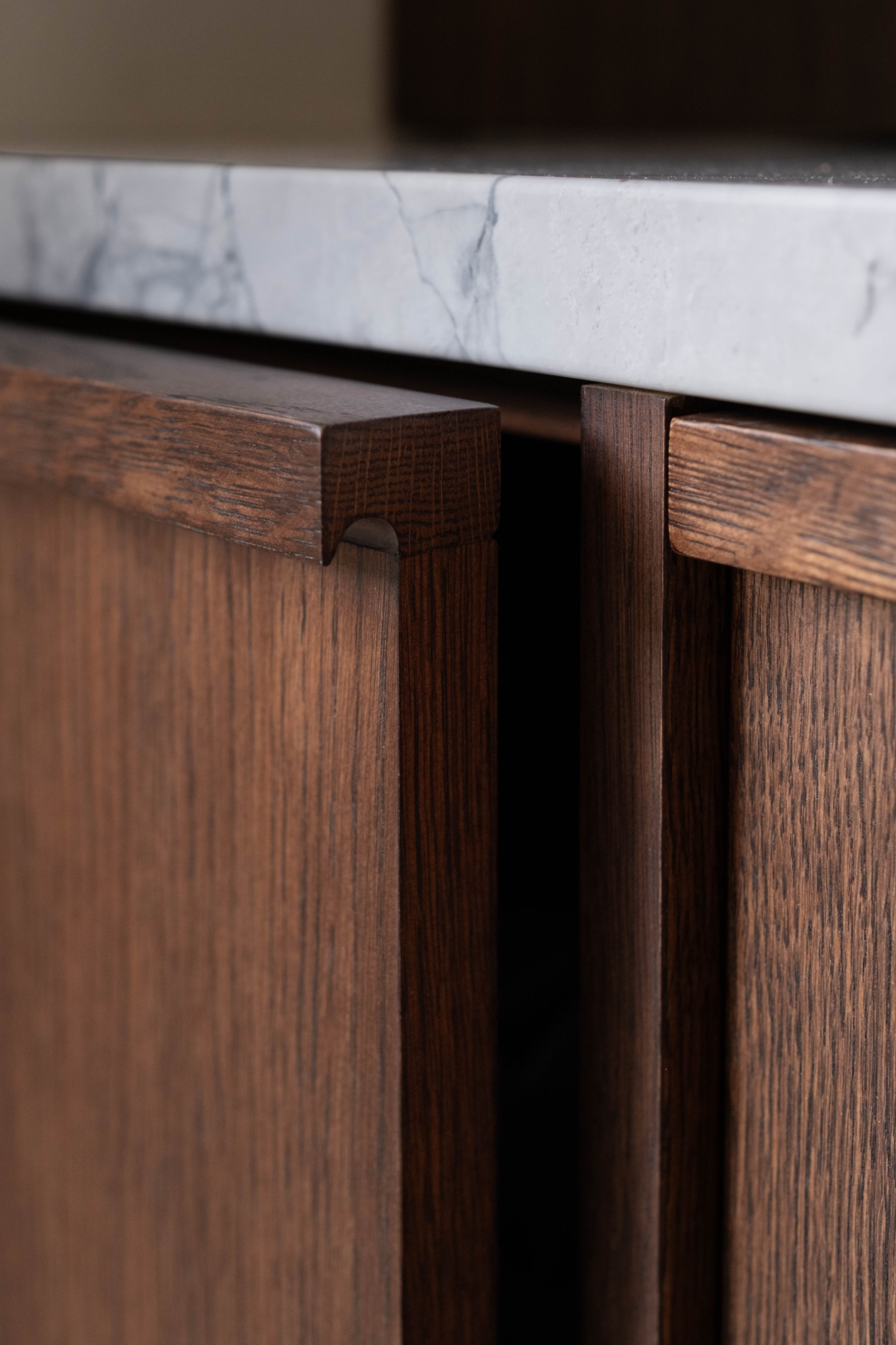Close-up of wooden cabinet doors beneath a marble countertop.