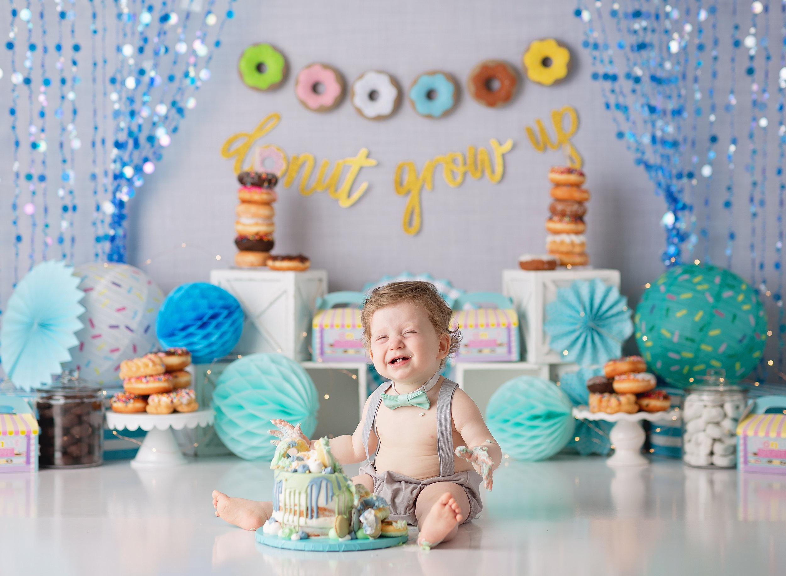  Happy baby with a donut cake and donut decor behind him 