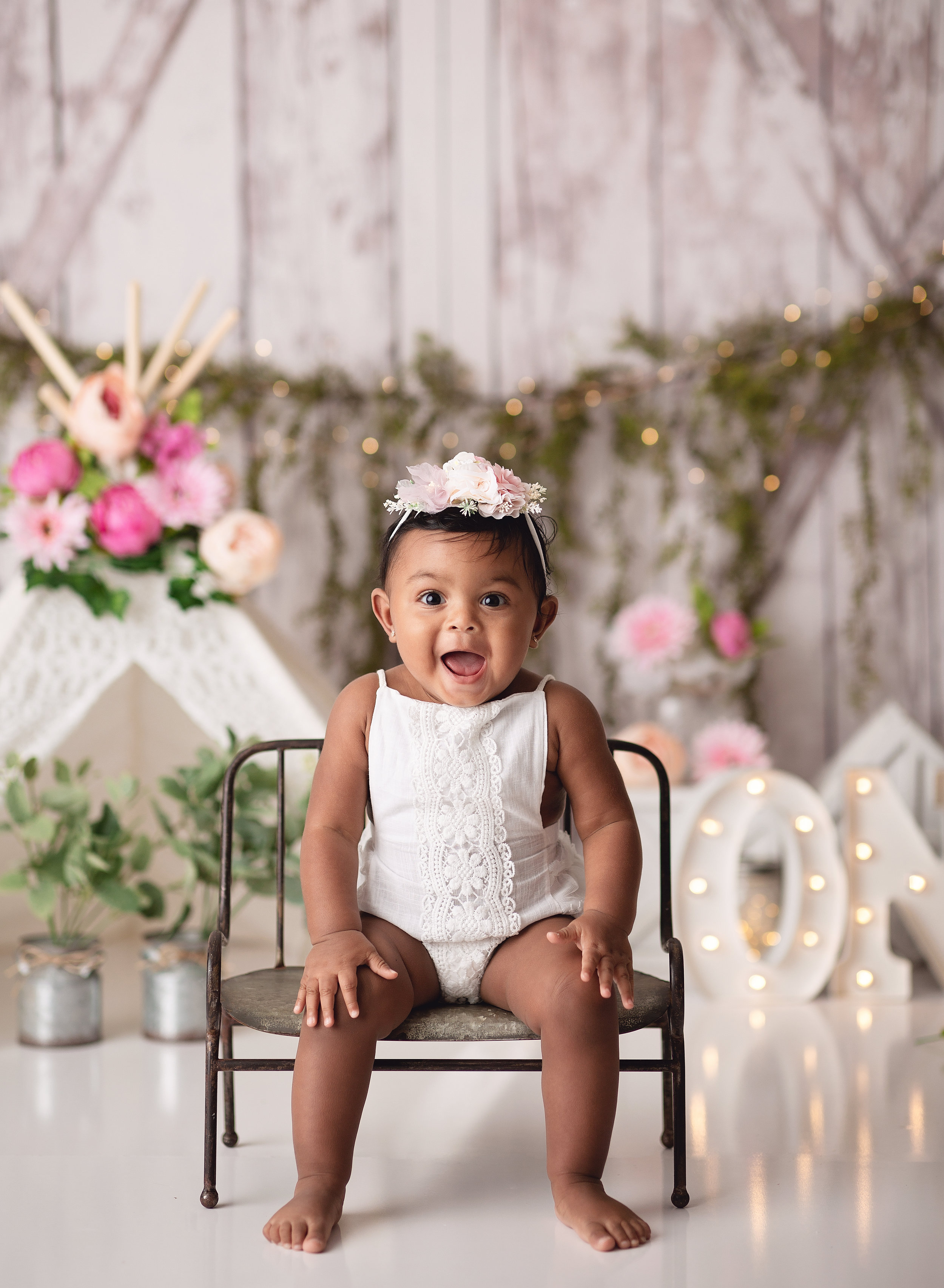  Toddler on miniature bench with flowers behind her 