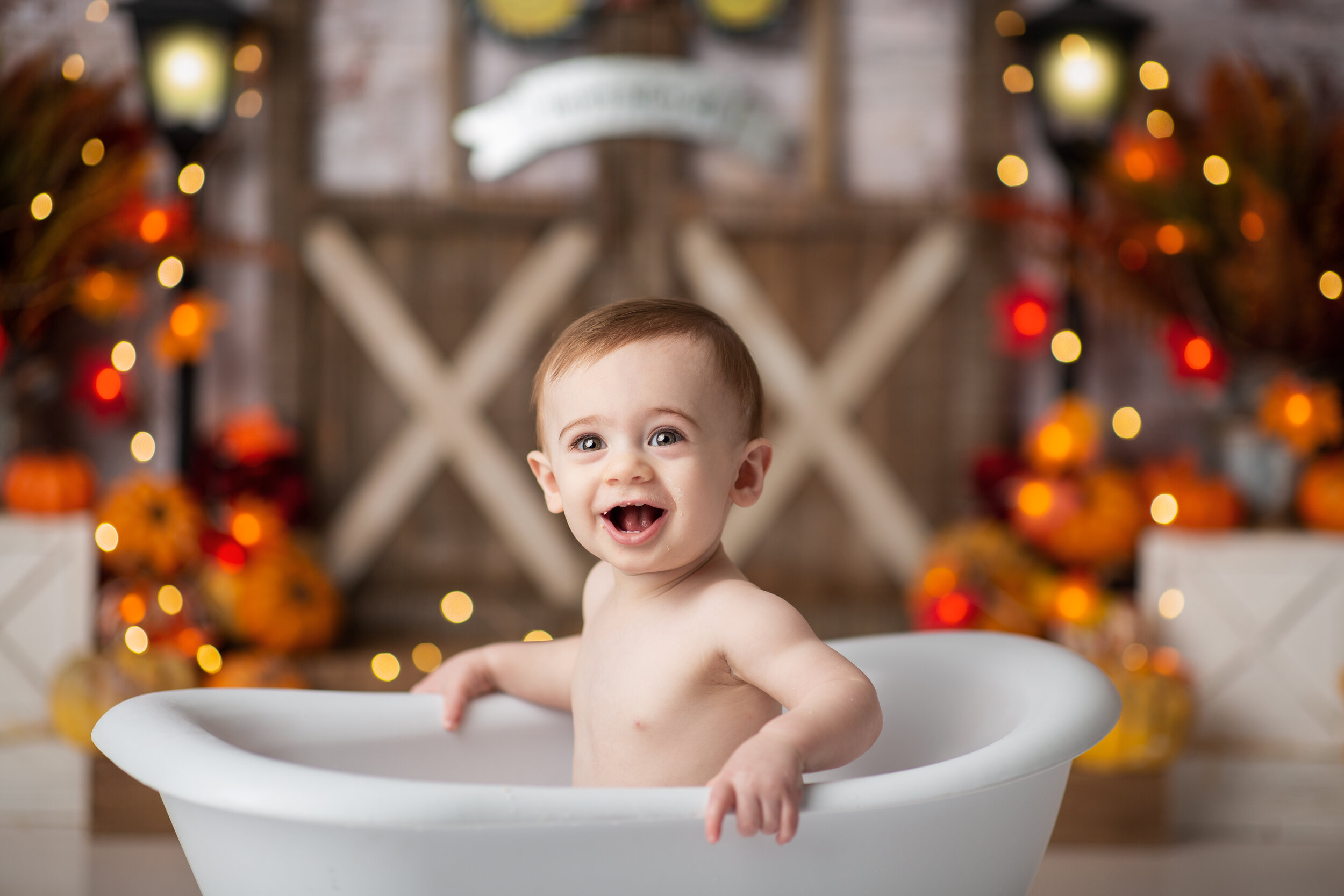  Smiling baby in miniature bathtub getting cleaned up after eating his birthday cake 