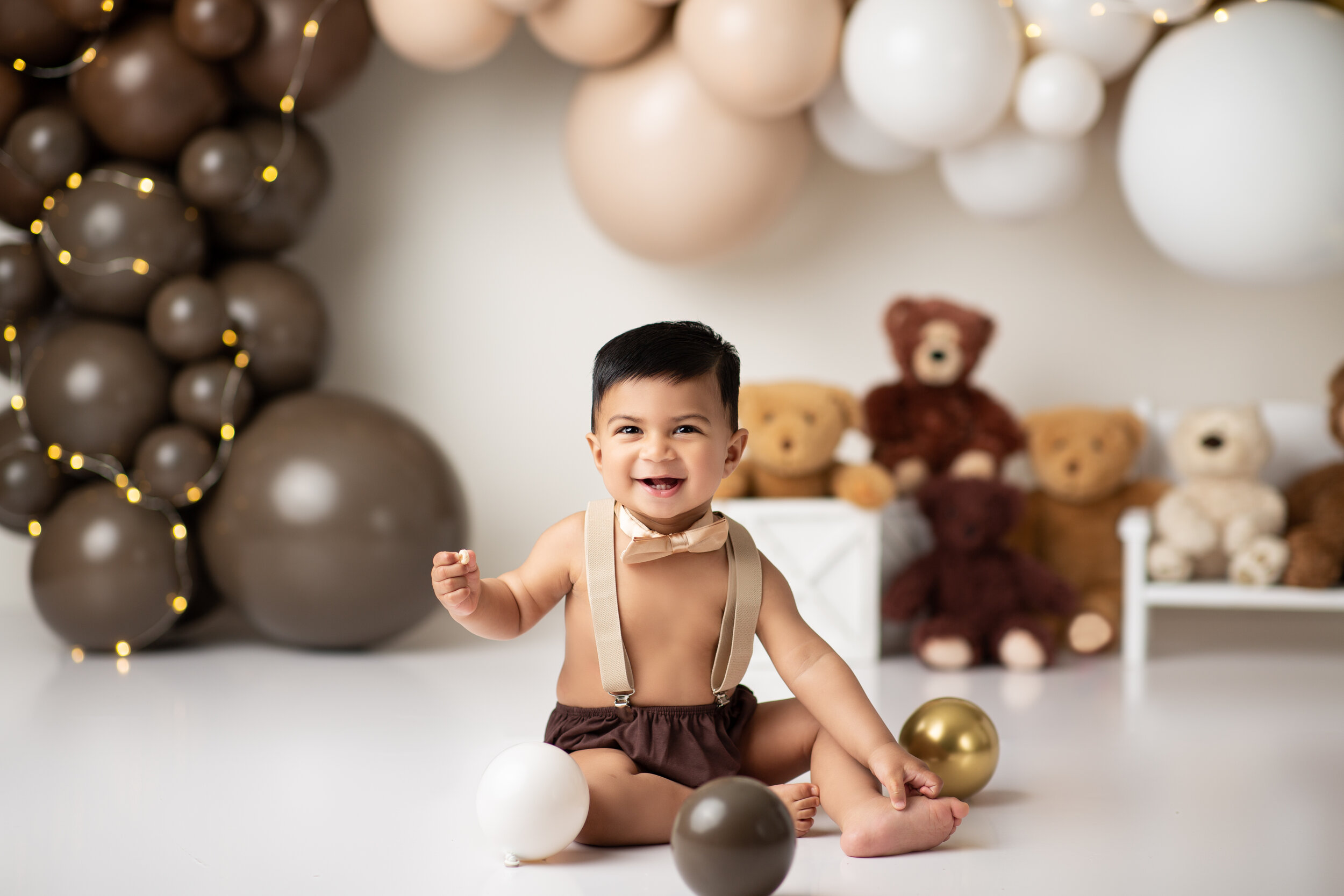  Toddler boy gets ready to celebrate his first birthday with balloons and teddy bears 