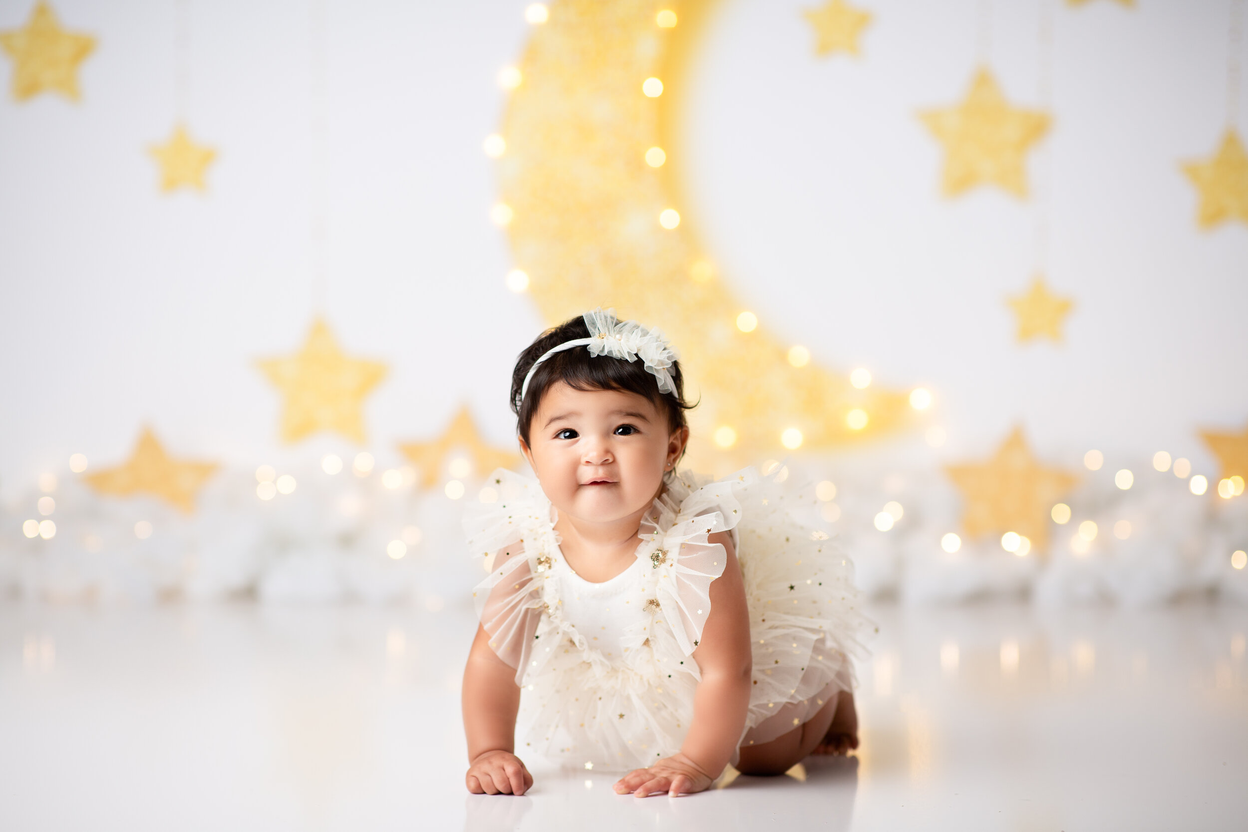  Baby crawls across the floor of a studio in New Jersey, with custom stars and moon cutouts on the wall behind her 