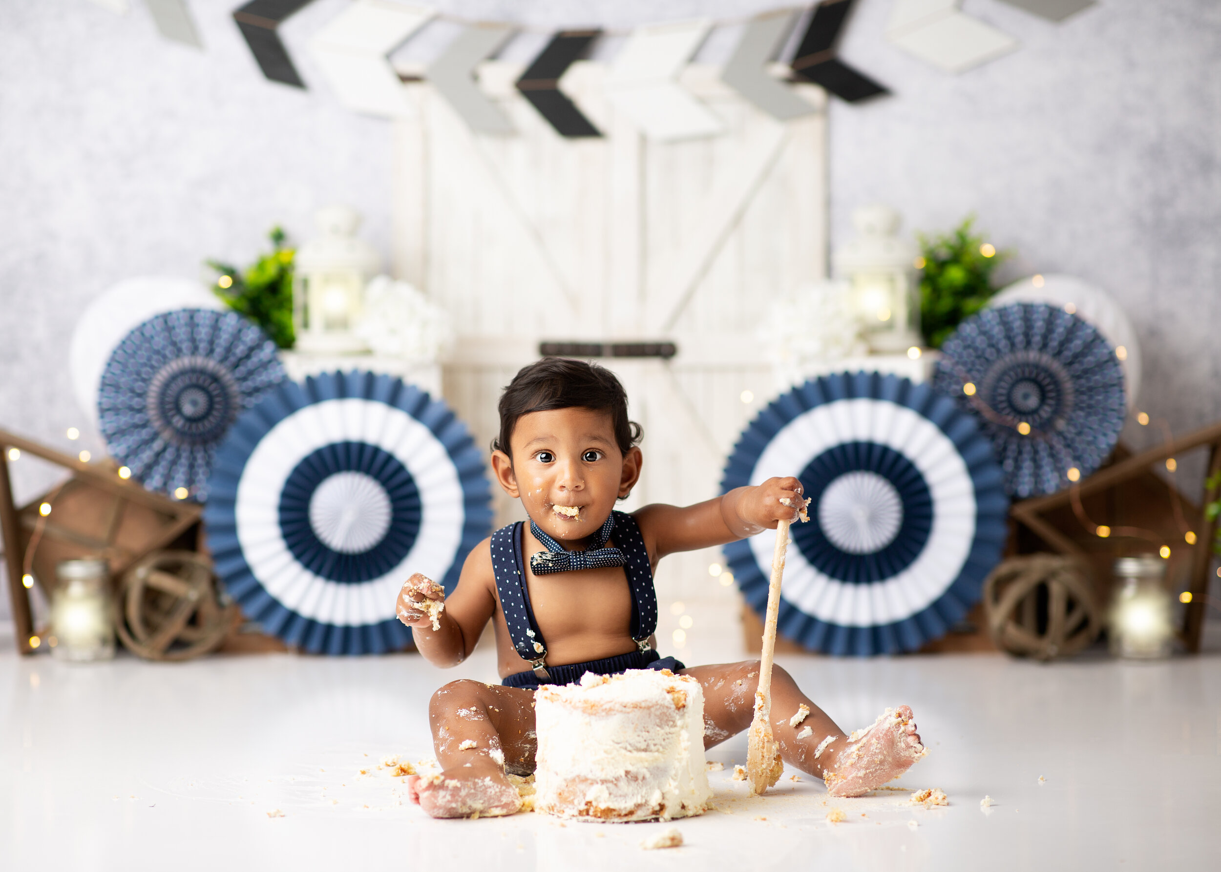  Baby boy digs into his birthday cake with a big wooden spoon 