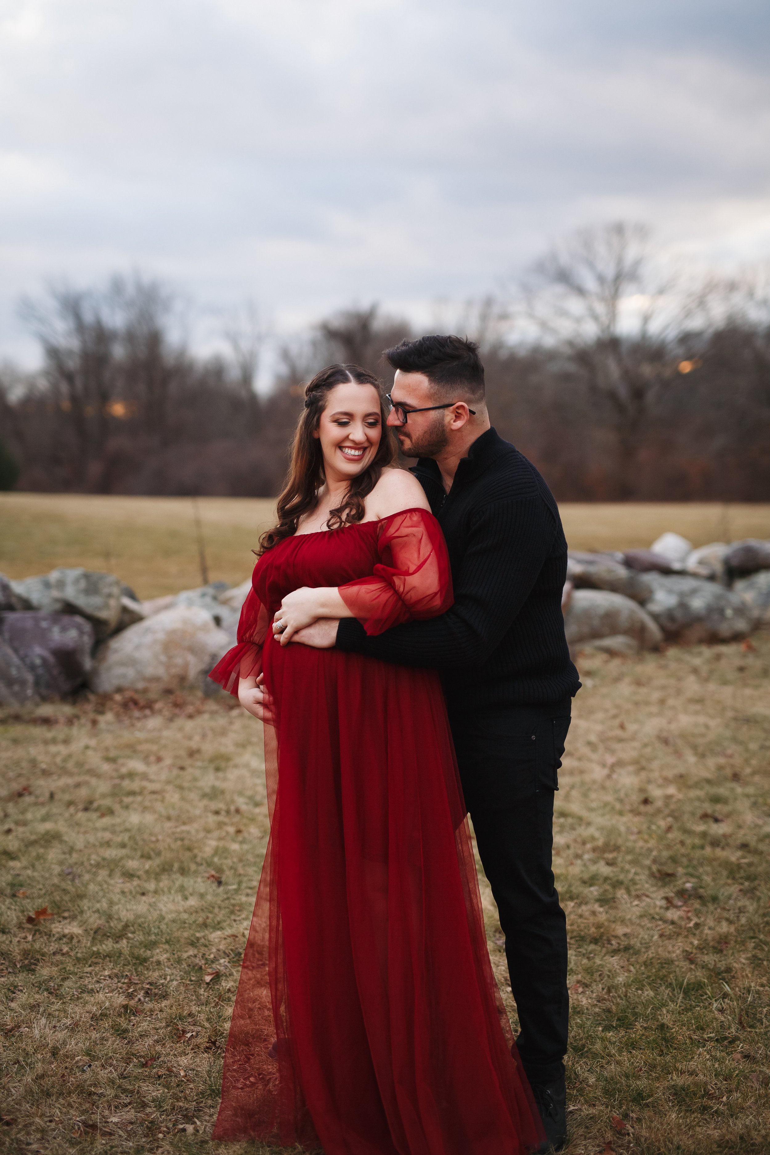  Husband embraces wife from behind during an outdoor maternity photoshoot in New Jersey 